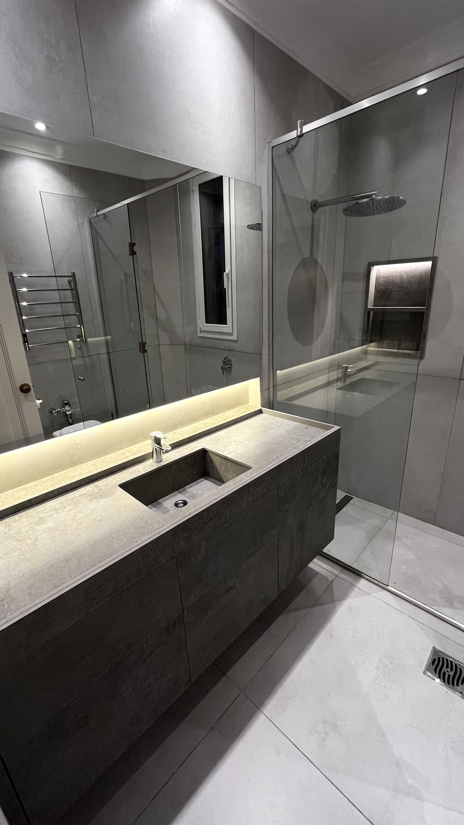 Baño moderno con microcemento, bacha integrada y ducha de vidrio — proyecto CASA CERRITO (German Salas arquitectura), por German Salas arquitectura - San Isidro, en Buenos Aires