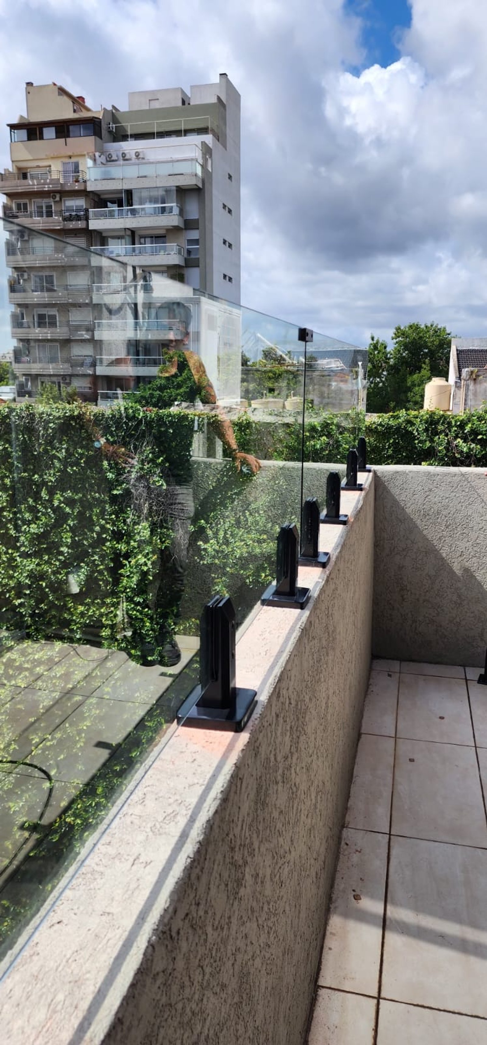 varanda com guarda-corpo de vidro e parede verde — projeto Baranda templada con pinzas, por Cristalcenter, em Villa Luro