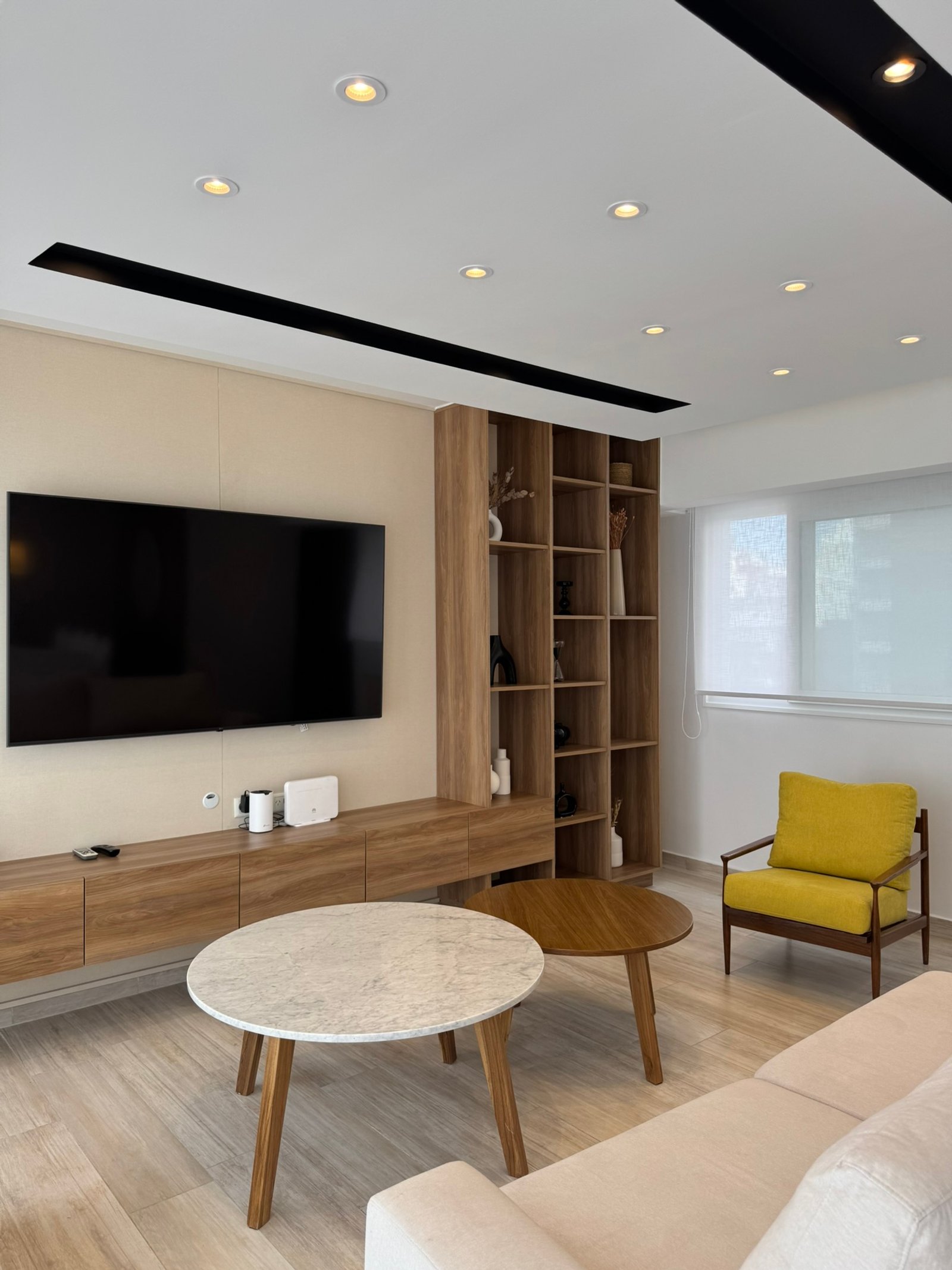 Living moderno con estanterías de madera y mesa de centro redonda — proyecto Apolinario, por MDBK Arquitectura, en Villa Crespo
