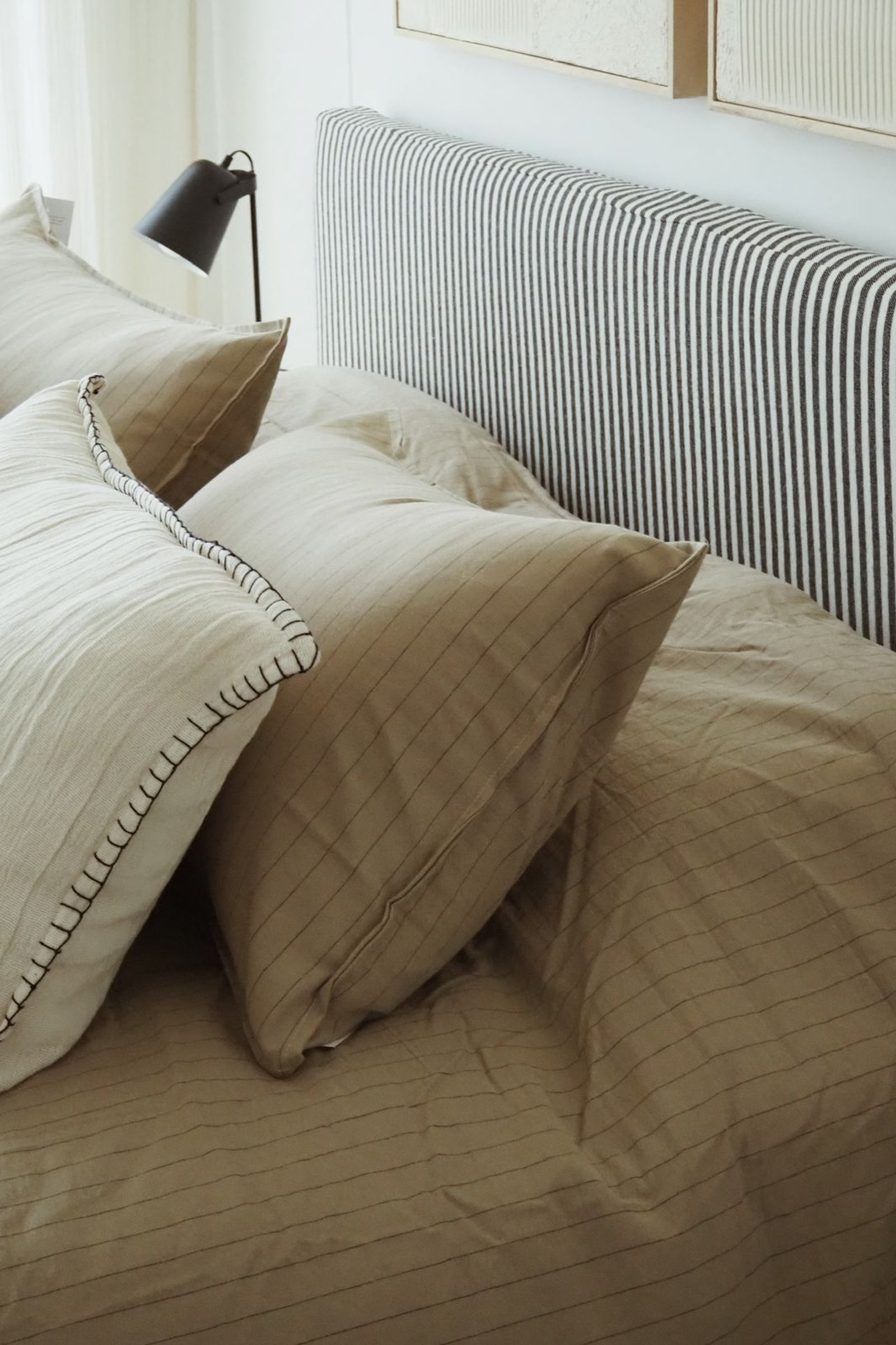 Dormitorio moderno con cabecero a rayas y almohadas texturizadas — proyecto RIO, por APATHEIA, en Provincia de Buenos Aires