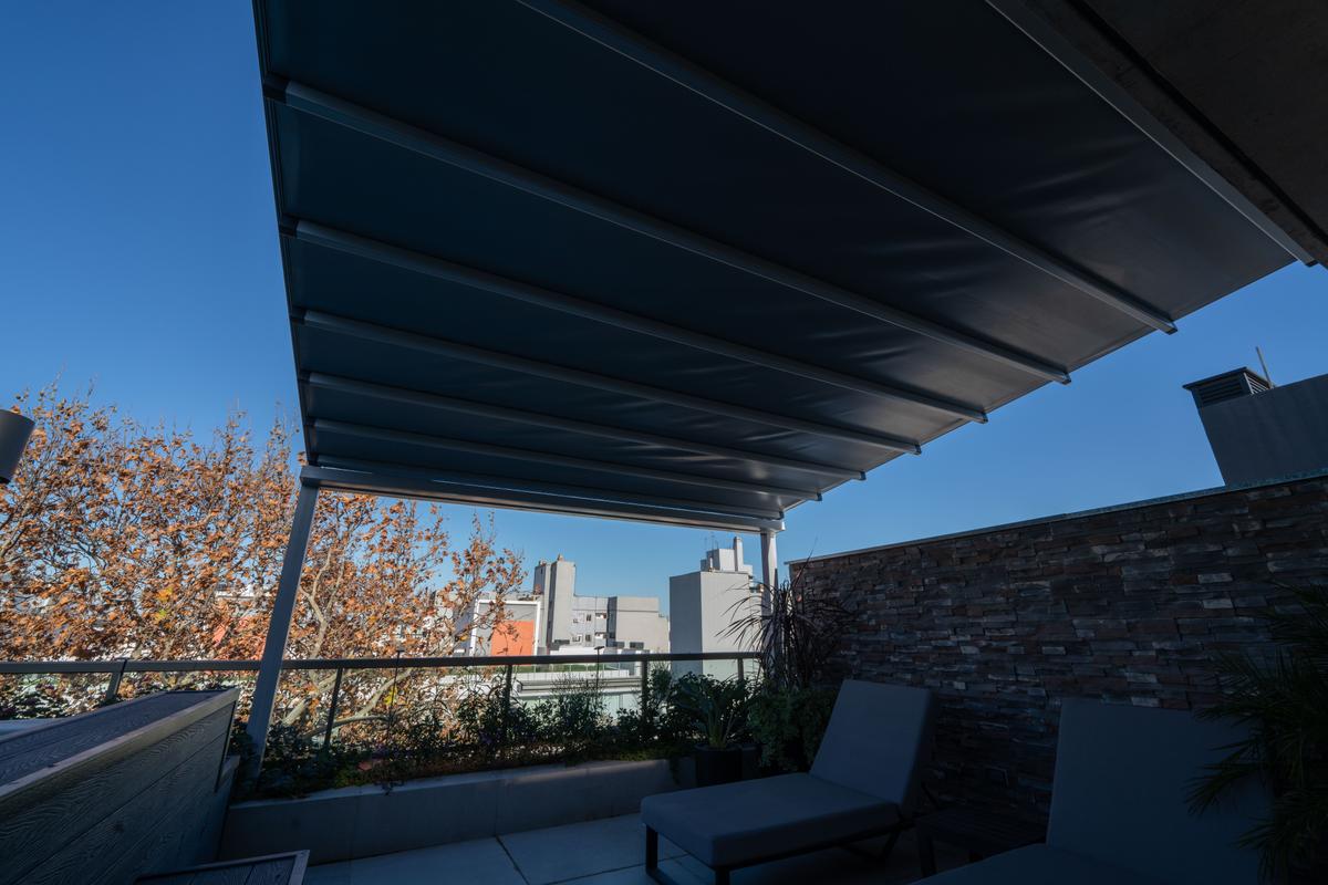 Terraço de varanda moderno com toldo retrátil e vista urbana — projeto TOLDER - PERGOLAS, por Argentina en Obra 2024, em Rincón de Milberg