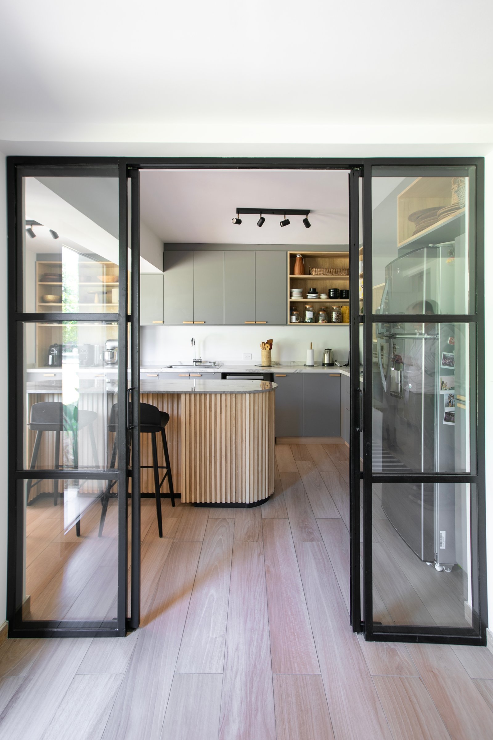 Cocina moderna estilo escandinavo con isla curva de madera y puertas de vidrio — proyecto PROYECTO CAT COURREGES, por ILVA, en Provincia de Buenos Aires