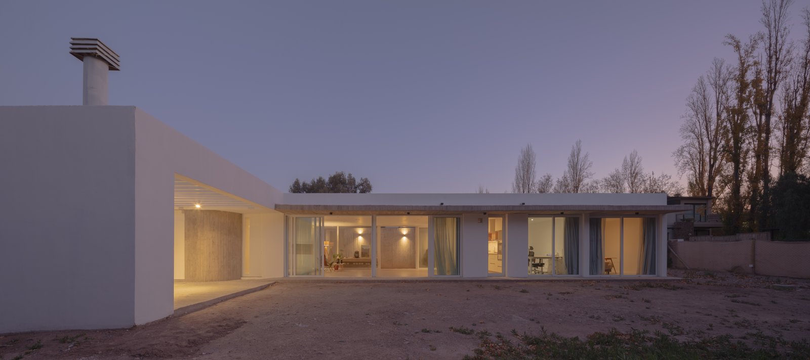 casa moderna blanca con grandes ventanales al atardecer — proyecto Vivienda CCE, por ONA - Oficina Nómada de Arquitectura, en M5505 Chacras de Coria