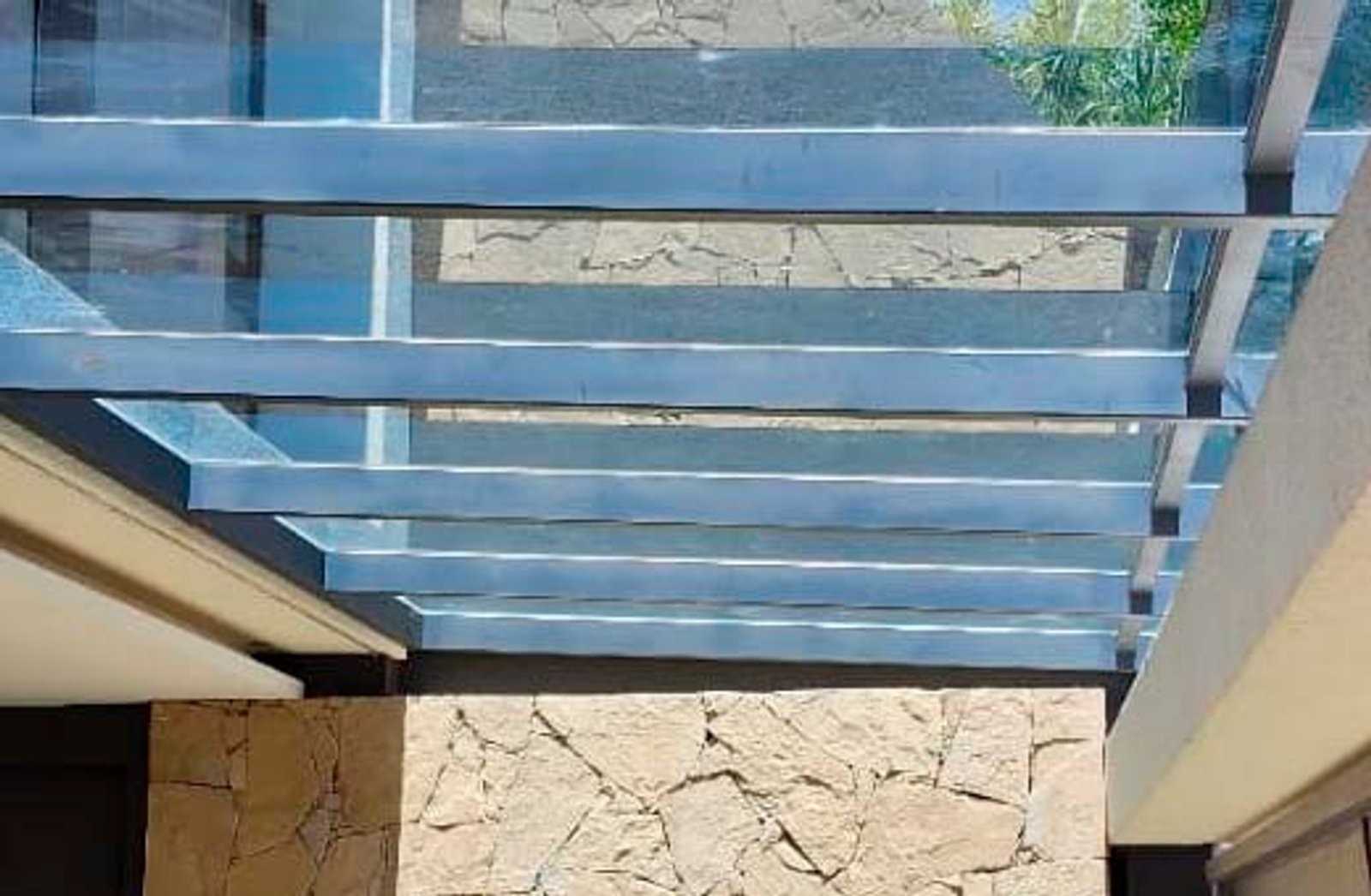 Terraza con pérgola de vidrio y detalles en piedra — proyecto Techos en vidrio laminado, por Cristalcenter, en Parque Leloir