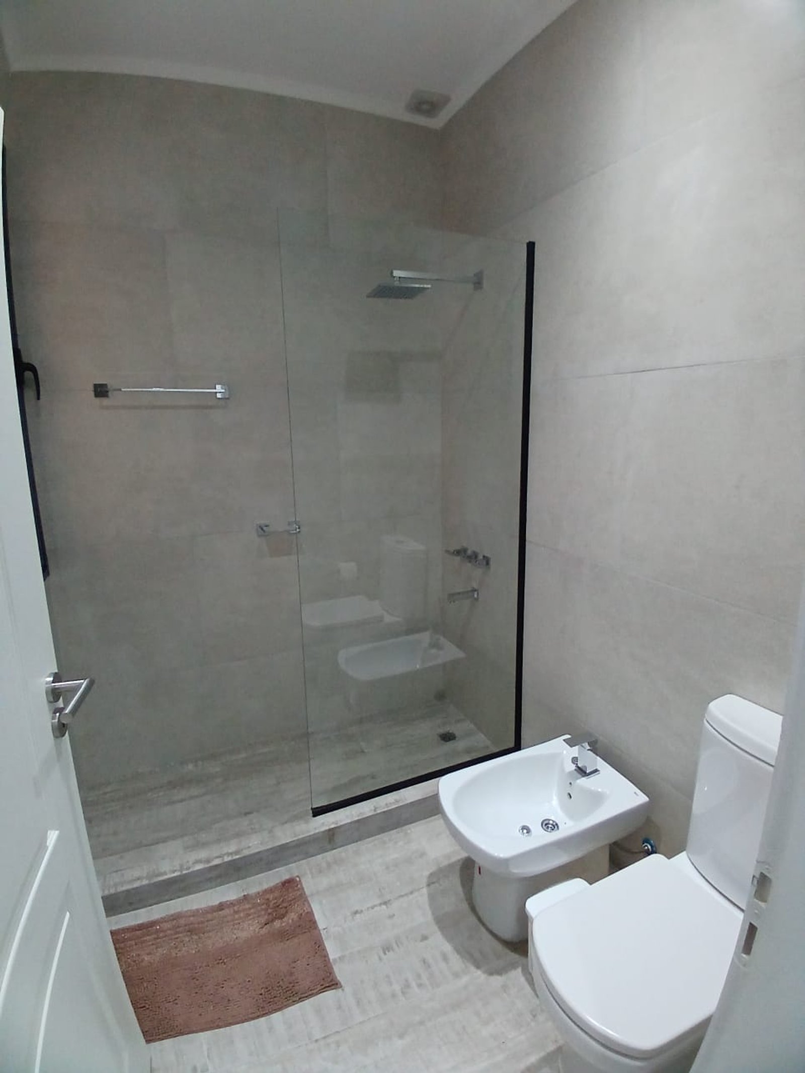 Baño moderno con bidet, ducha de vidrio y revestimientos grises — proyecto CASA A Y M, por Sep Arquitectura , en Ruta 205 Km 53