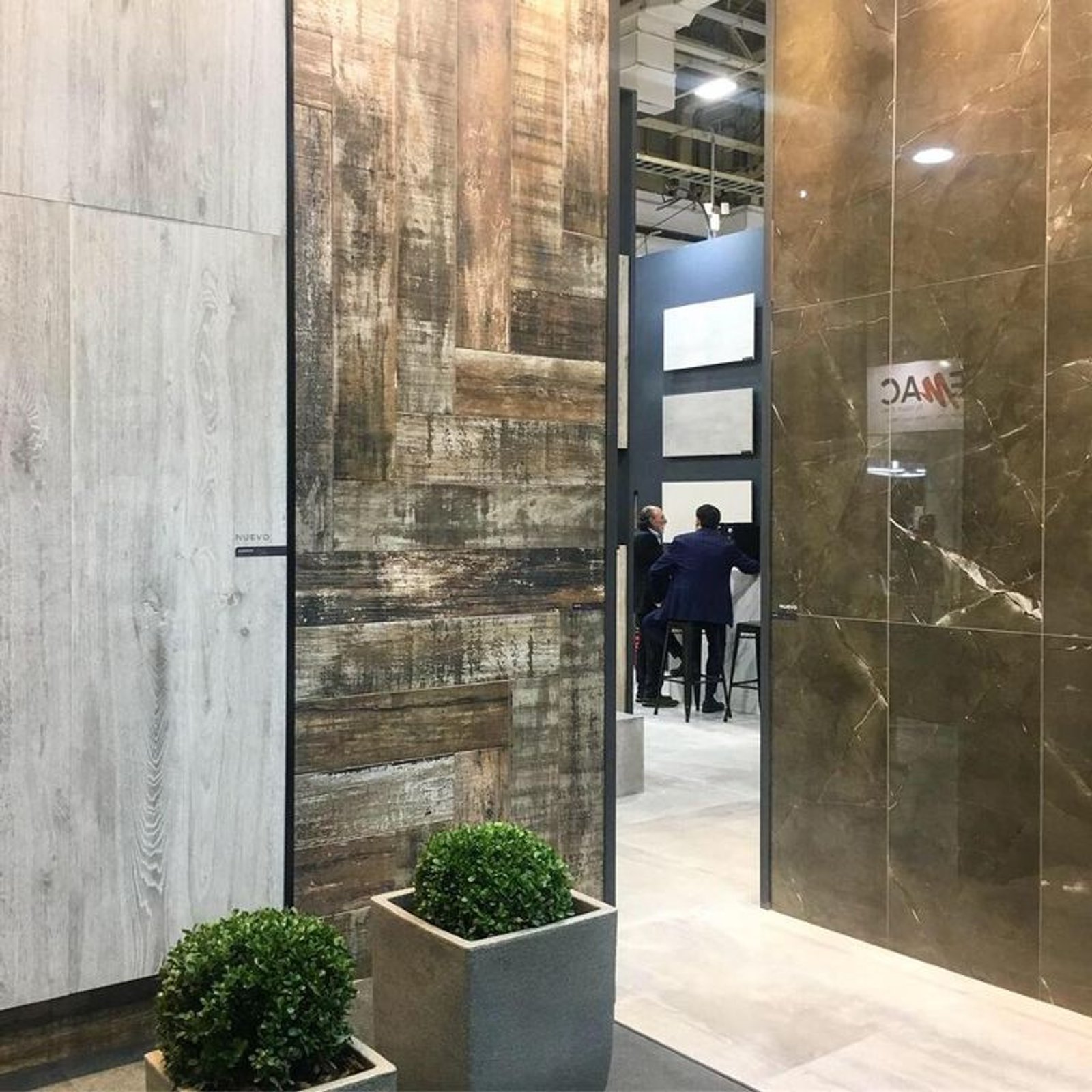 espacio comercial con paneles de madera rústica y baldosas de mármol — proyecto Expo Revestir 2019, por Vite Porcellanato, en São Paulo
