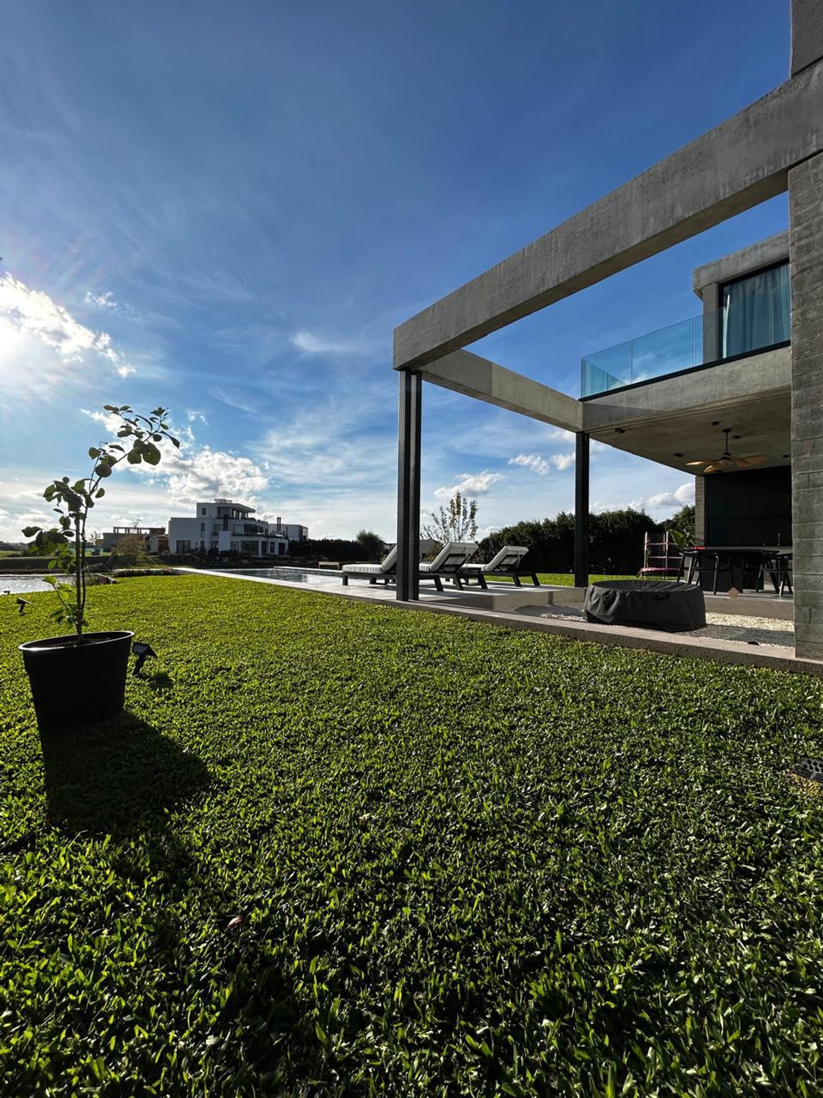 Casa moderna de hormigón con césped exuberante y cielo azul — proyecto Casa Residencial la isla nordelta, por Cynodon, en Av. de la Isla
