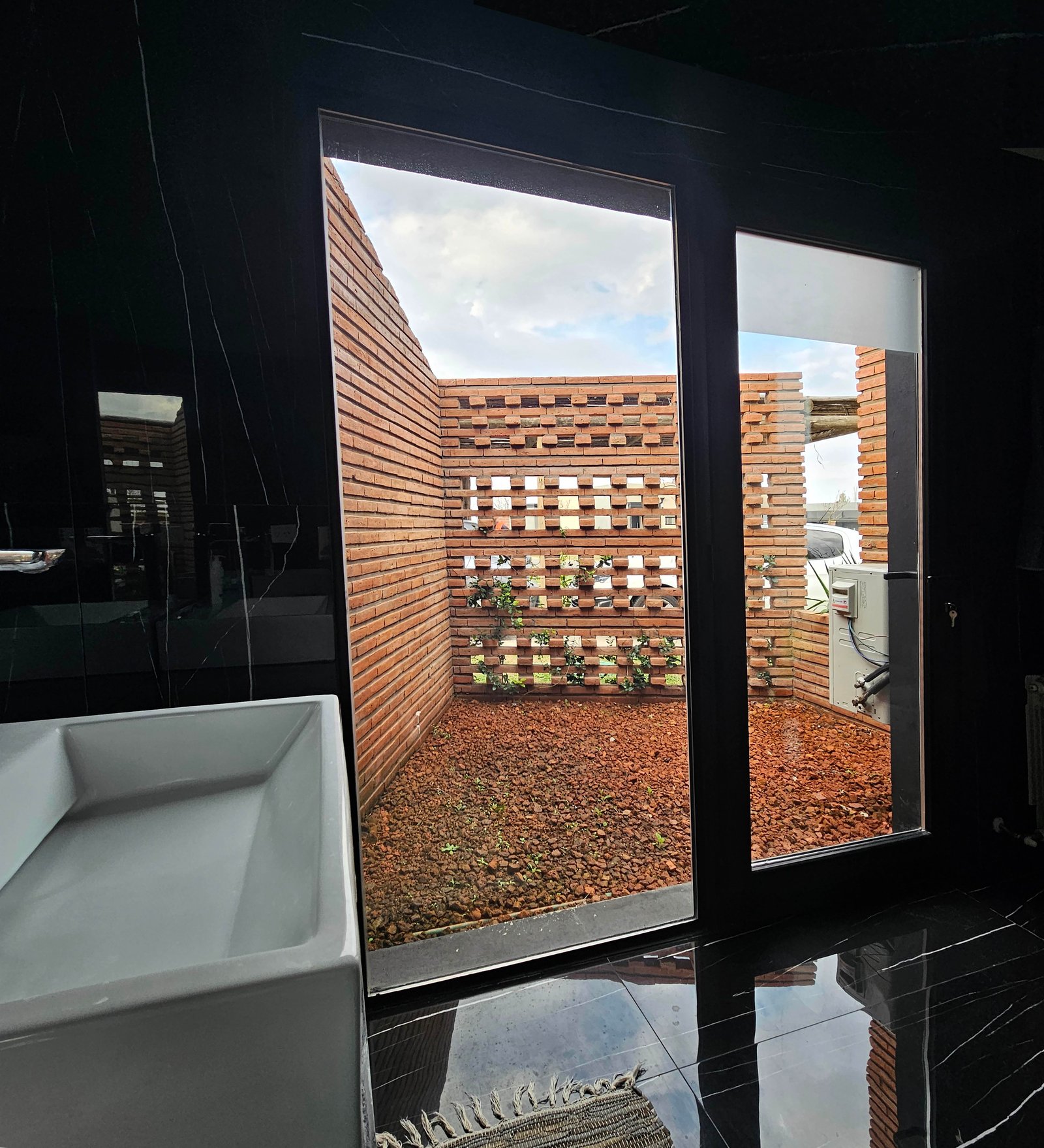 Patio moderno con pared de madera y ladrillo, visto desde interior con bacha — proyecto SS01-House, por Etunez, en Provincia de Buenos Aires
