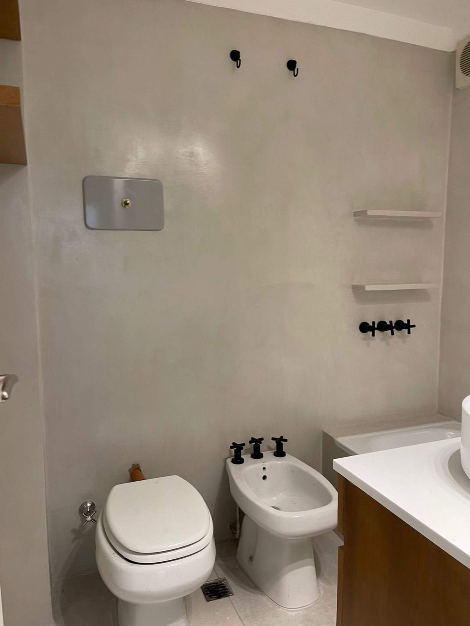 Banheiro moderno minimalista com paredes de microcimento e torneiras pretas — projeto Olazabal, por Estudio NET Arquitectura, em Olazábal 3228