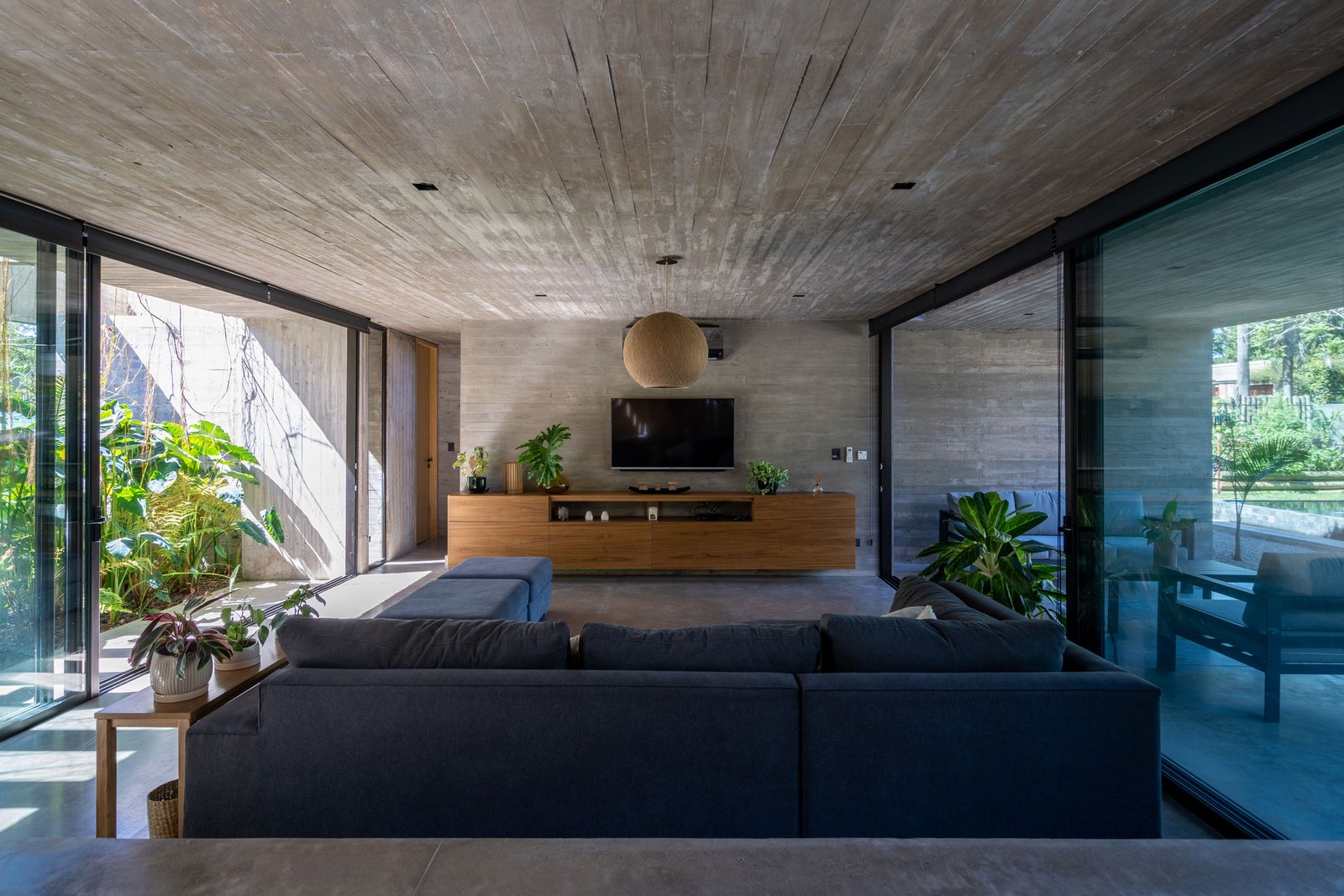 Living moderno con hormigón expuesto y grandes ventanales — proyecto Casa Leloir, por Besonías Almeida arquitectos, en Parque Leloir