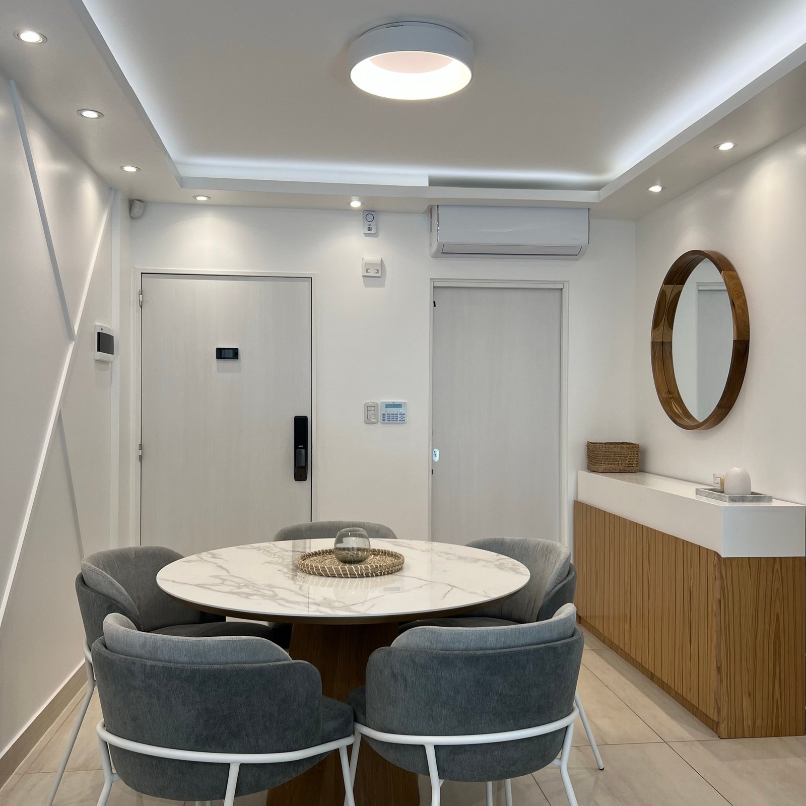 Comedor moderno con mesa redonda de mármol sintético y sillas grises — proyecto Basualdo II, por MDBK Arquitectura, en Liniers
