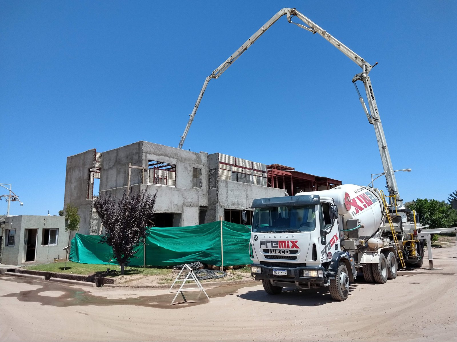 camión mixer y grúa en obra de hormigón visto — proyecto Proyecto A-F, por TERROC, en Luján de Cuyo