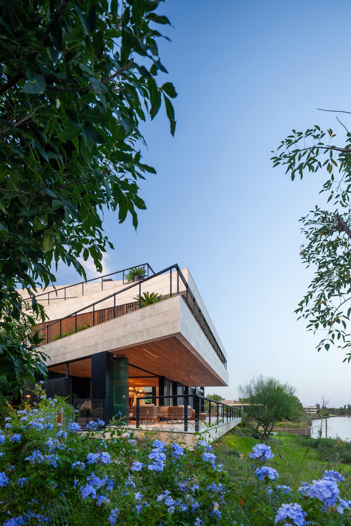 fachada moderna com pedra bege e vegetação exuberante — projeto Casa Porsche, por Remy Arquitectos, em Buenos Aires