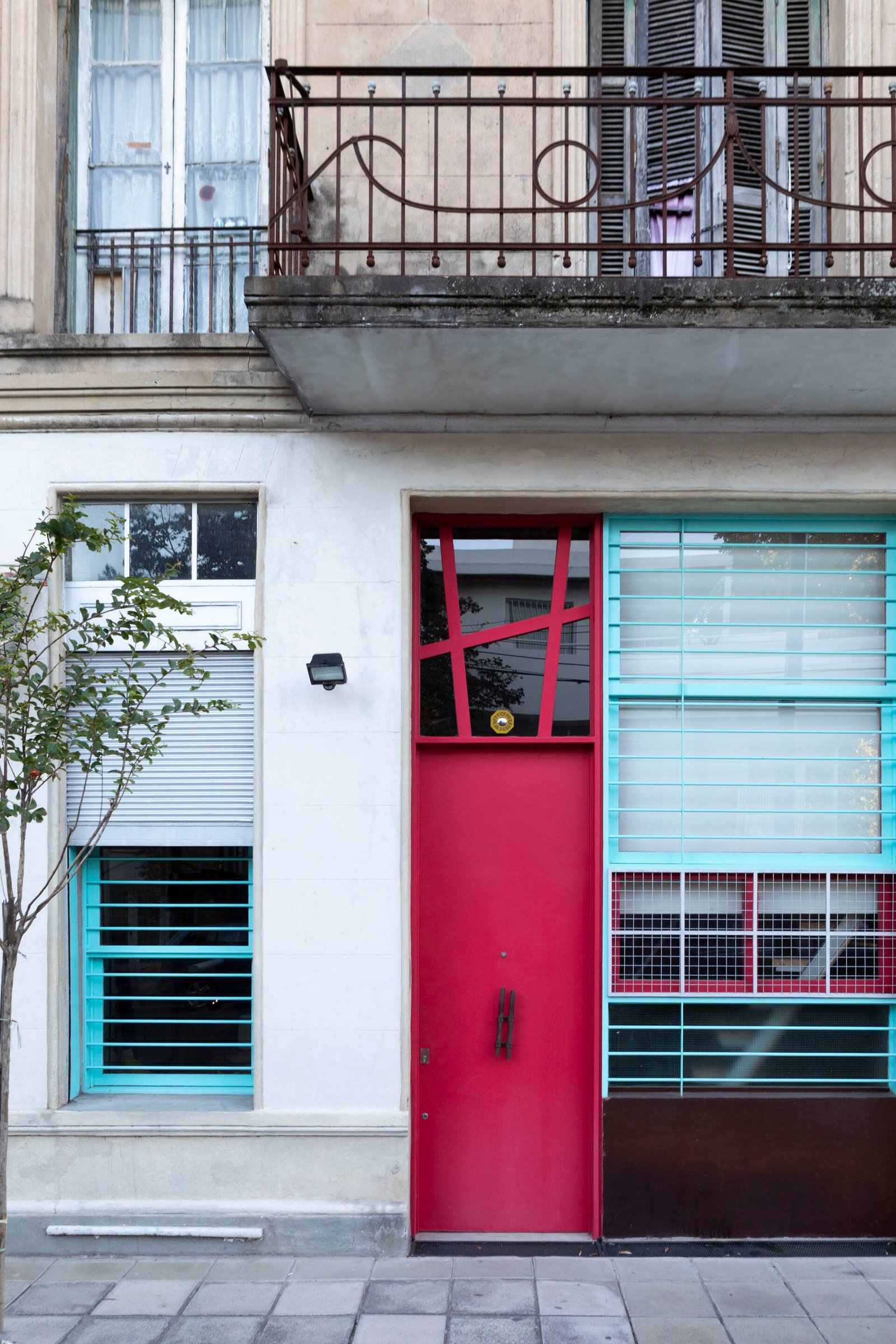 Fachada moderna com porta vermelha vibrante e janelas coloridas — projeto Casa Arcos, por Silvia Soqueff, em Núñez