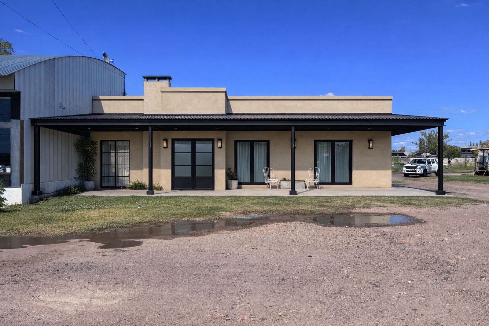Fachada moderna con patio amplio y techo de metal negro — proyecto Reforma Total - Ampliacion, por Atelier de Diseño Interior - Luján Macia, en Río Colorado