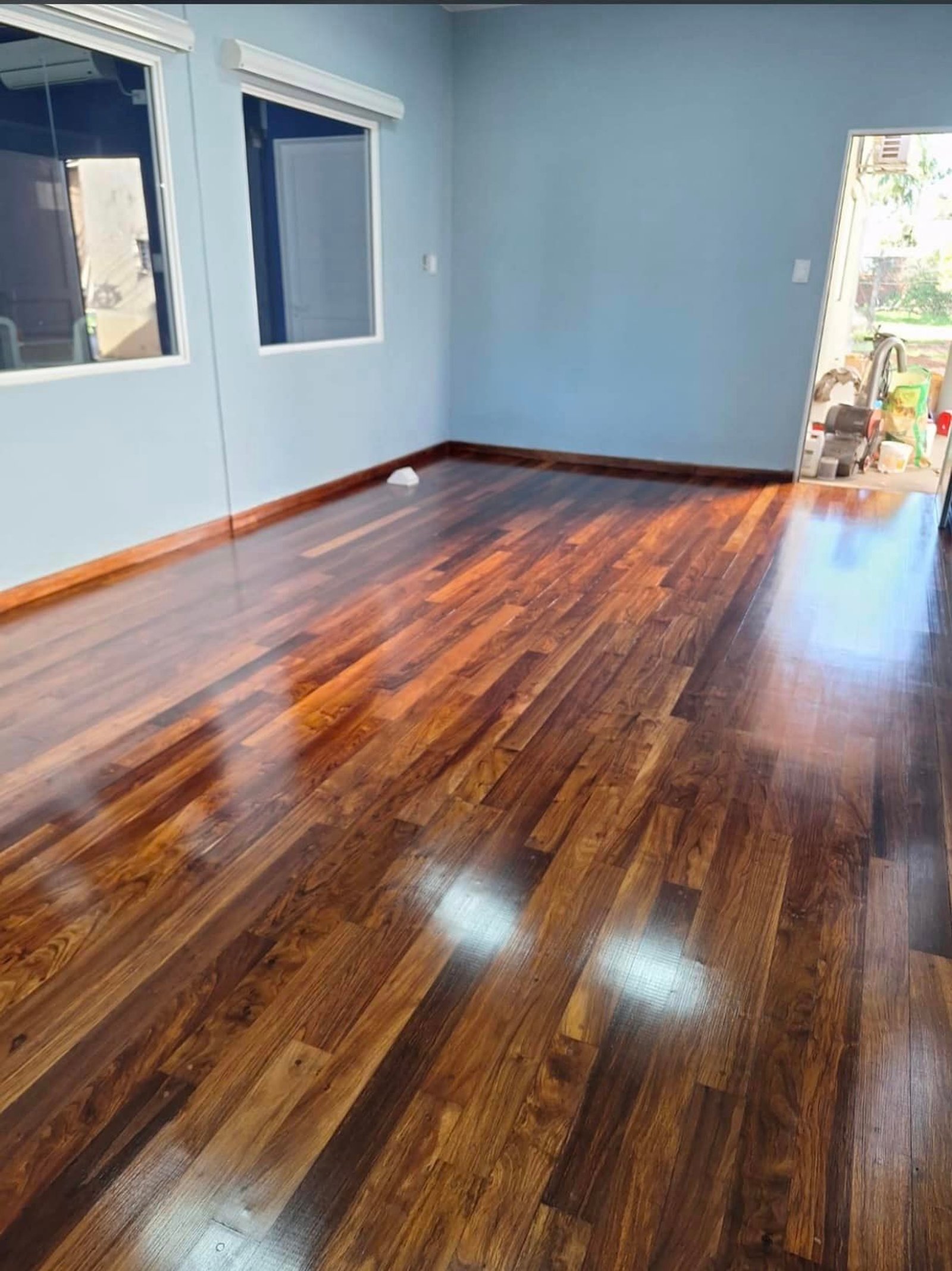 Sala com piso de madeira escura e paredes azuis — projeto Esudio Contable, por Arquitecto Gustavo Maidana, em Caá Catí