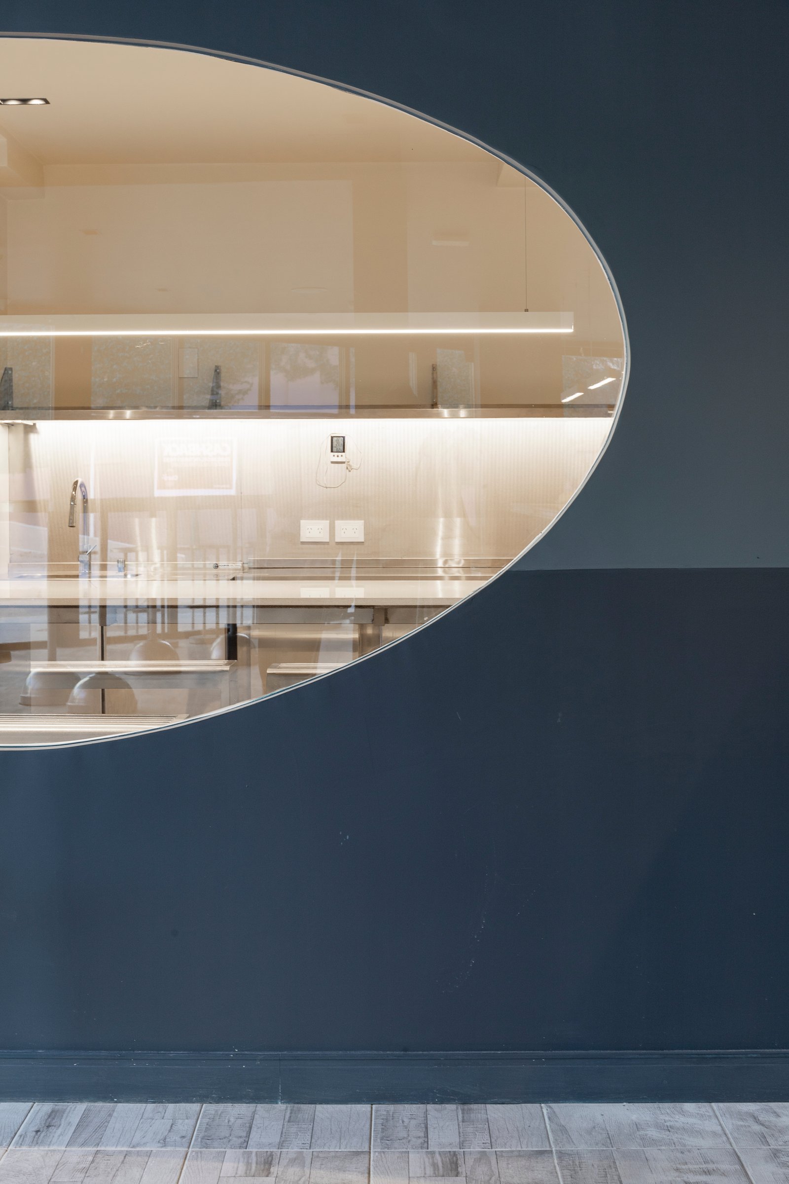 Interior de local comercial moderno con pared curva azul y exhibidores — proyecto KALYS PIZZA, por AB ARQUITECTURA, en Núñez