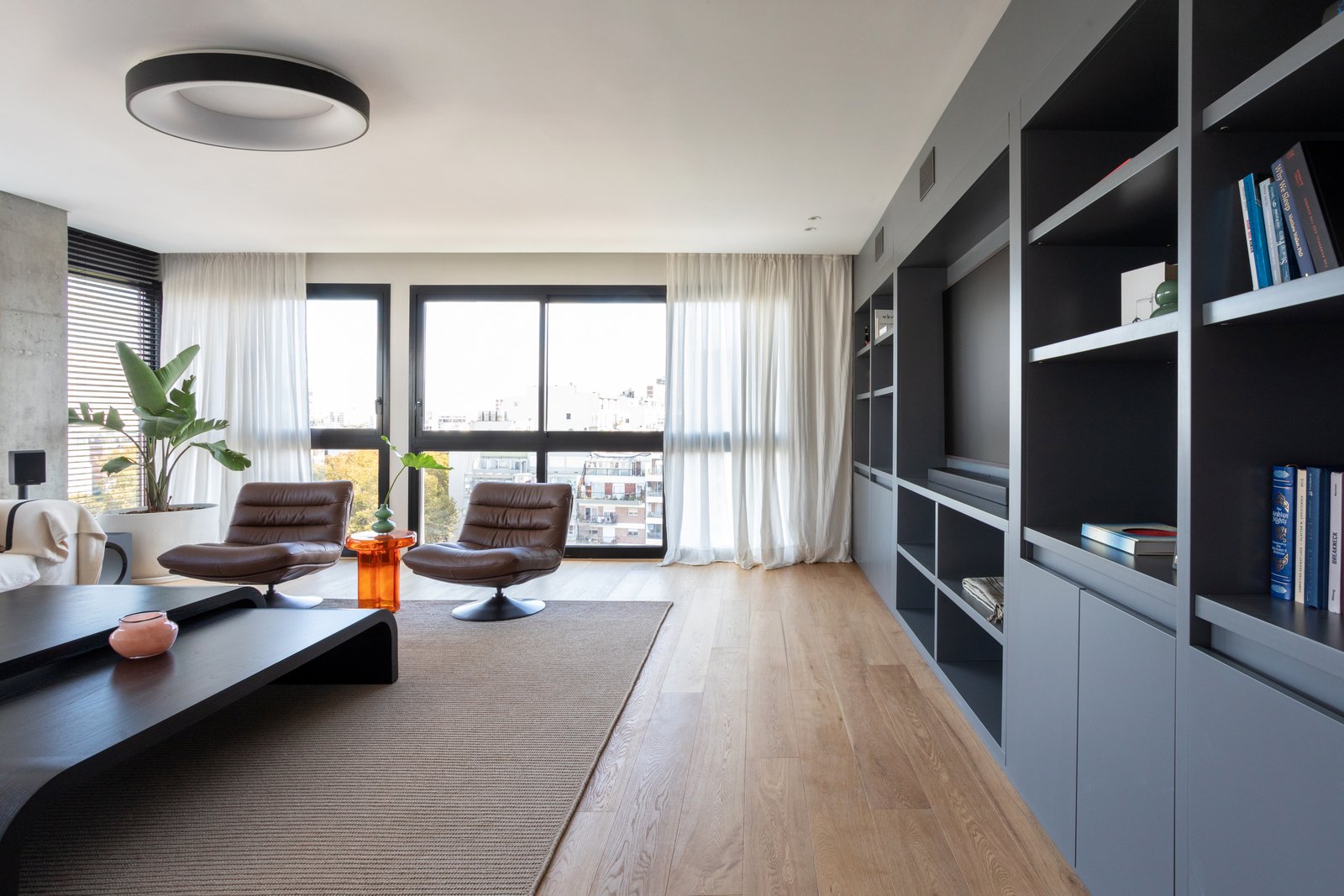 Living moderno con sillones de cuero y estantería negra — proyecto Vidal, por Estudio Losa, en Belgrano