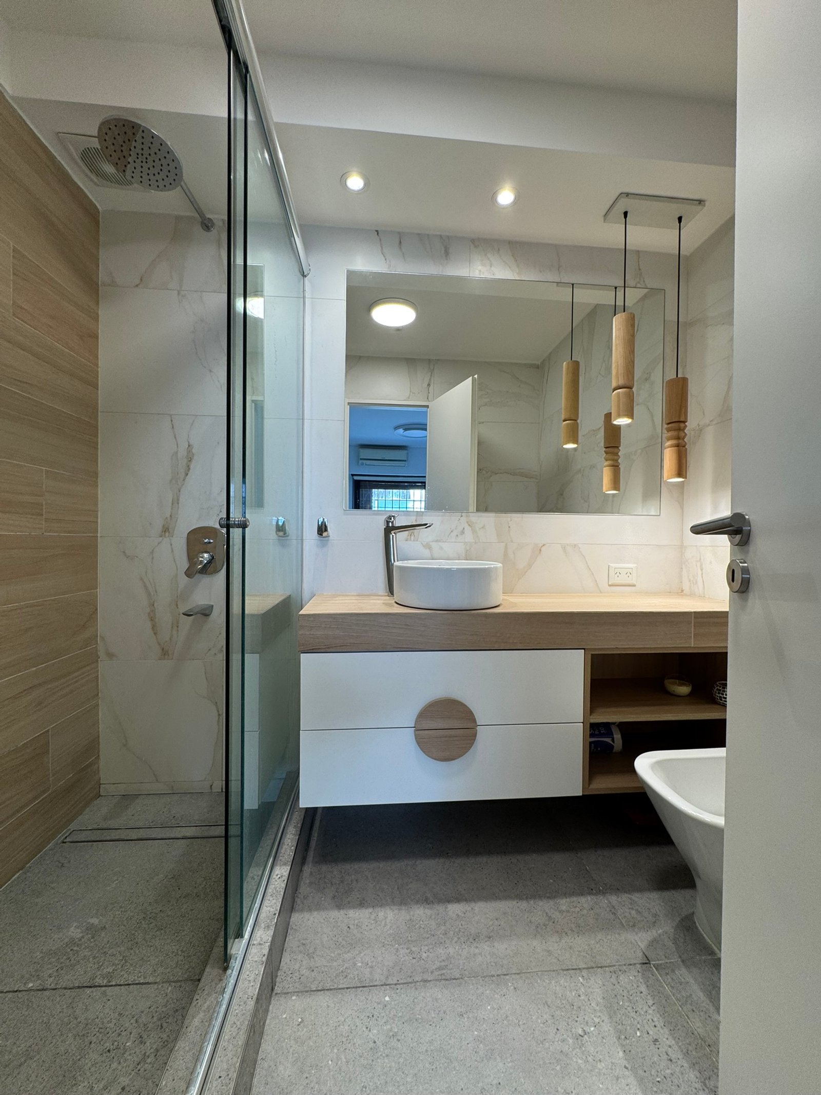 Baño moderno con revestimientos de mármol, madera y luces colgantes — proyecto Vera II, por MDBK Arquitectura, en Villa Crespo
