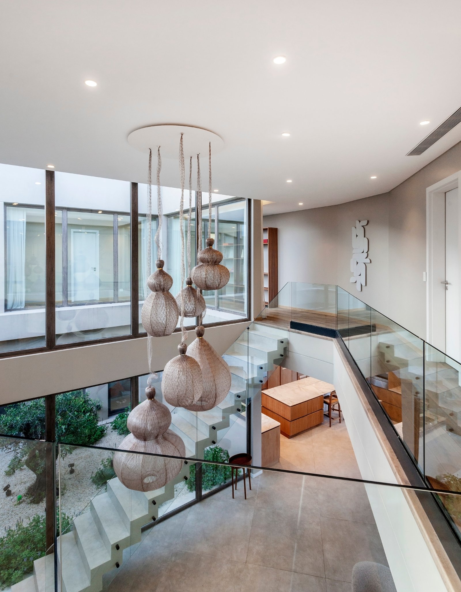Atrio moderno con escalera flotante y lámparas colgantes — proyecto CASA M40, por A'PRIMA - Arquitectura Sustentable, en Unnamed Road