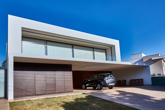 Casa moderna con fachada blanca, garaje integrado y auto estacionado — proyecto Casa Mast, por Toledo Arquitetura E Design