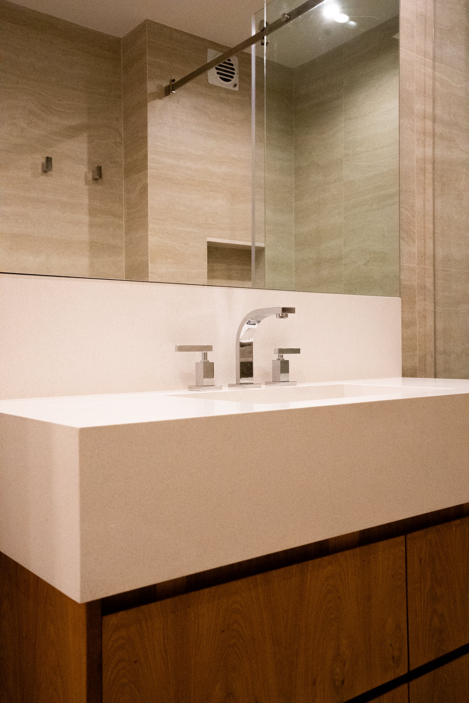 Baño moderno con revestimiento de piedra y mueble de madera — proyecto QUINTANA, por ESTUDIO TEZ, en Recoleta