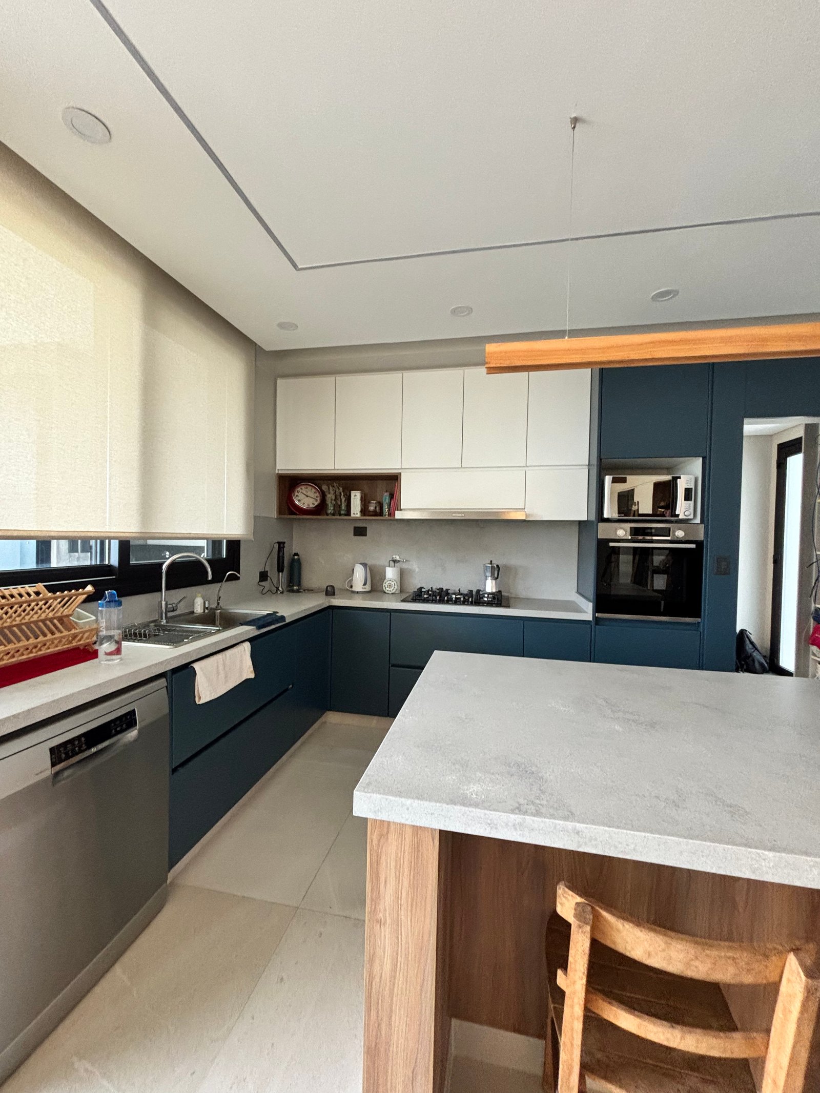 Cozinha moderna com ilha grande de pedra e armários azuis — projeto LOTE 020, por DIKKA Arquitecta, em San Vicente
