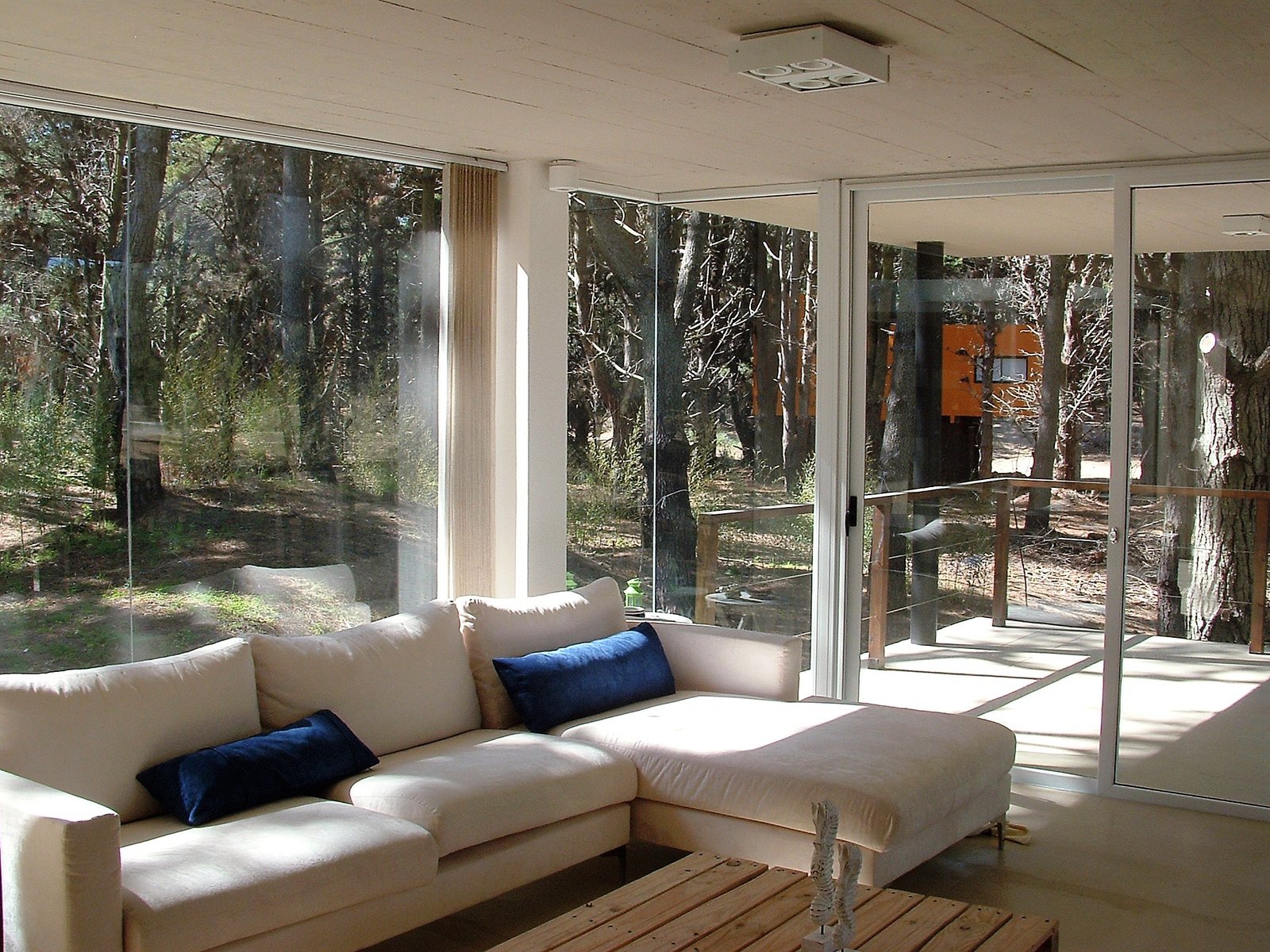 Living moderno con vistas al bosque y amplios ventanales — proyecto villa del puente, por GJF estudio, en Costa del Este