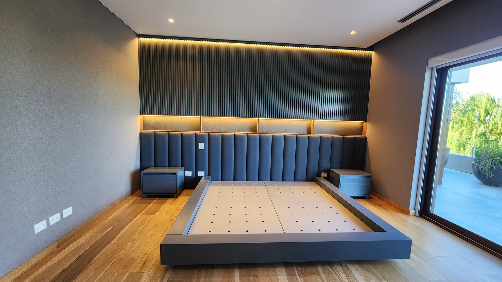 Quarto moderno com cama baixa e painéis cinzas — projeto Reforma El Golf, Nordelta, por Build a Home Arquitectura, em Avenida del Golf s/n