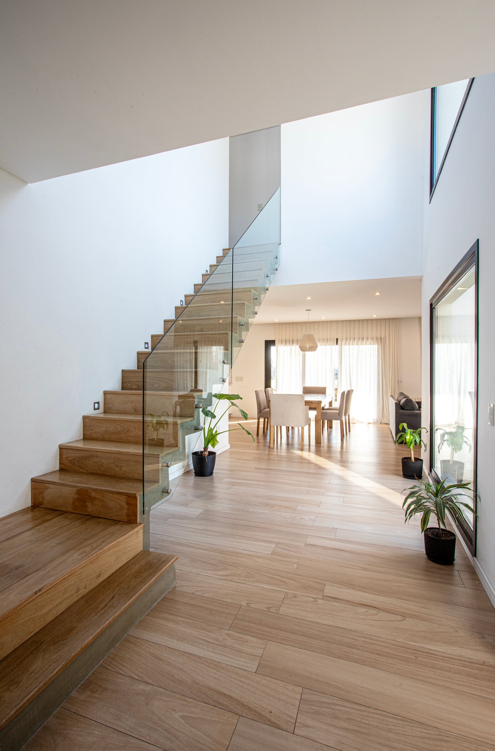 Escalera flotante moderna con atrio de doble altura y mucha luz — proyecto SS45, por EZ architects, en Pilar