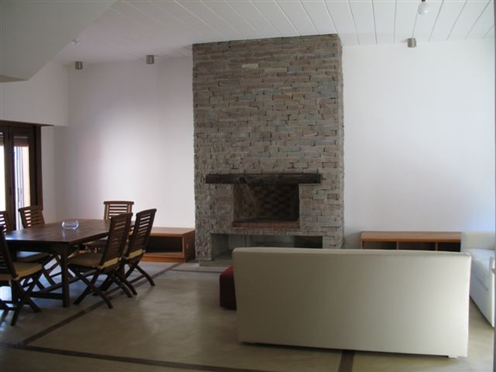 living comedor moderno con chimenea de piedra y piso de cemento — proyecto Departamento CABA, por PROTEX, en Buenos Aires