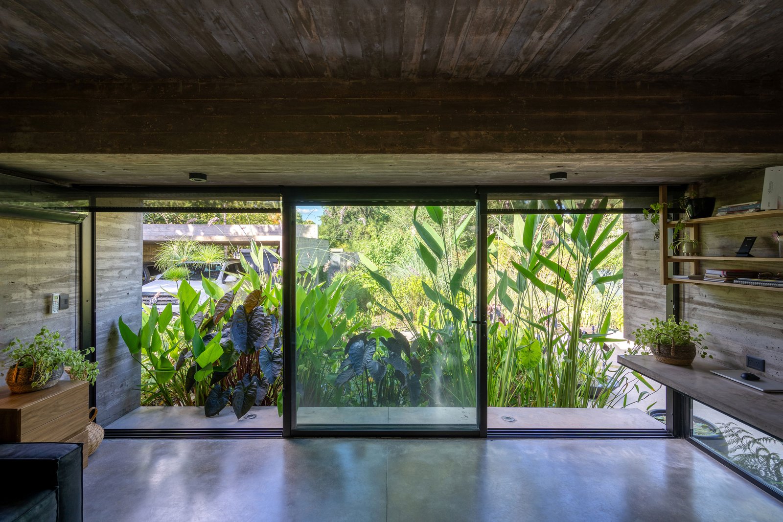Sala moderna com muito verde e concreto aparente — projeto Casa Leloir, por Besonías Almeida arquitectos, em Parque Leloir
