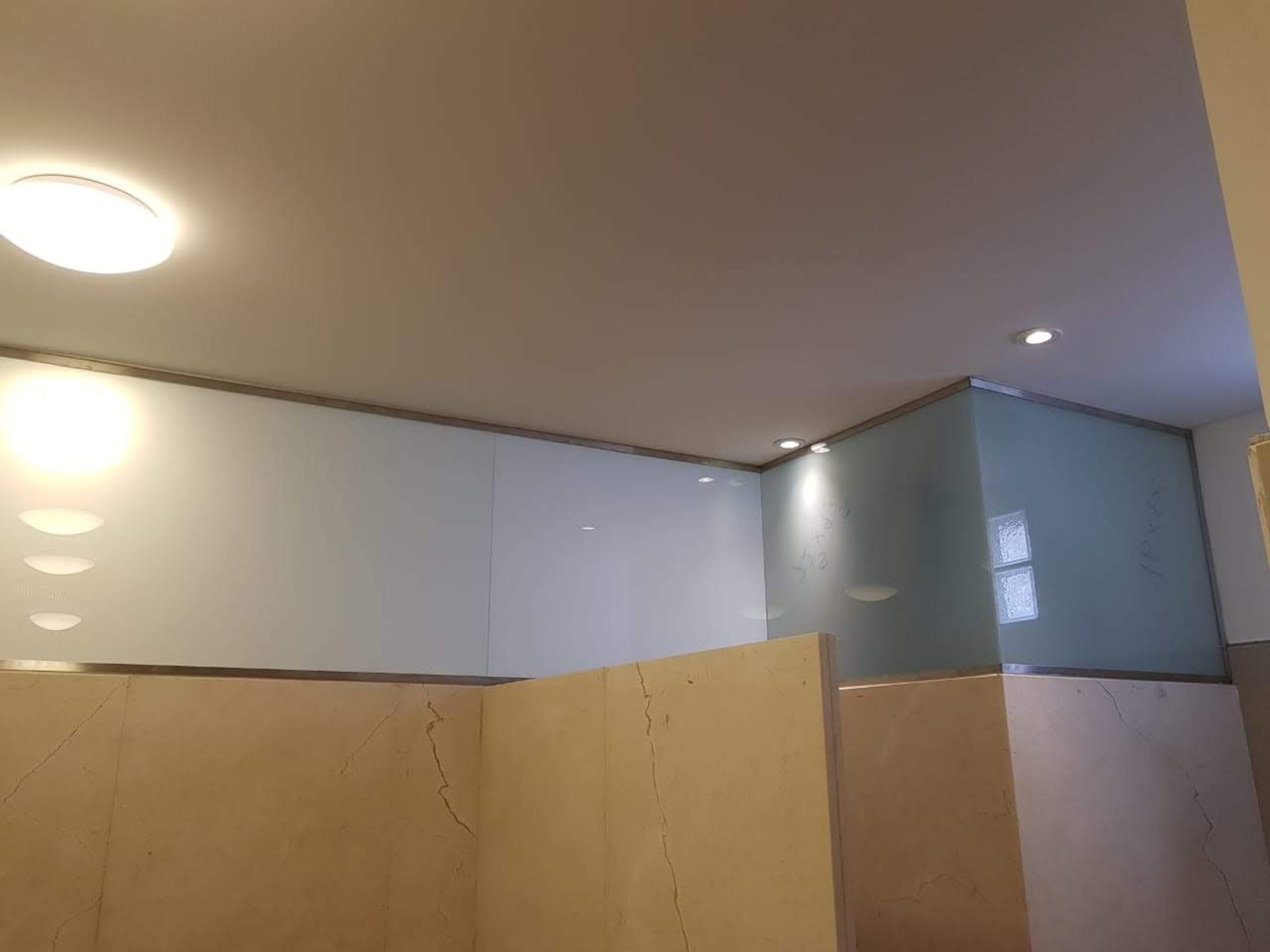 Baño moderno con paredes de vidrio esmerilado y mármol beige — proyecto Paños fijos laminados esmerilados Blindex, por Cristalcenter, en Balvanera