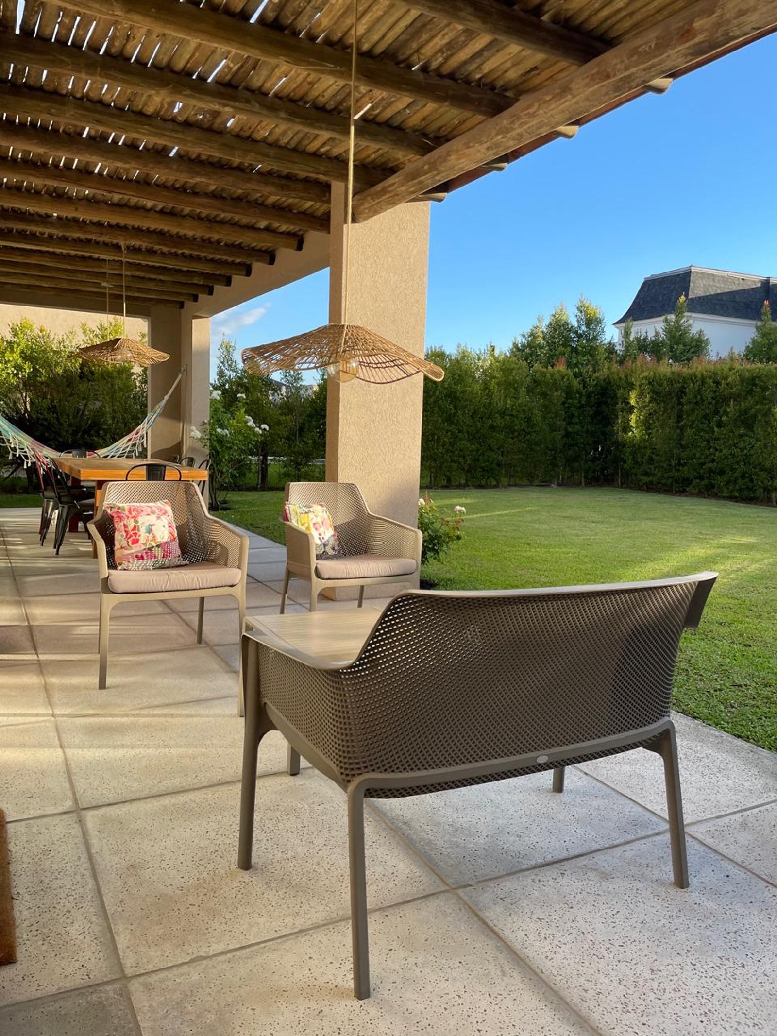 Parrilla moderna con pérgola, sillones de mimbre y piedra — proyecto Living Exterior, por Casa Nuñez