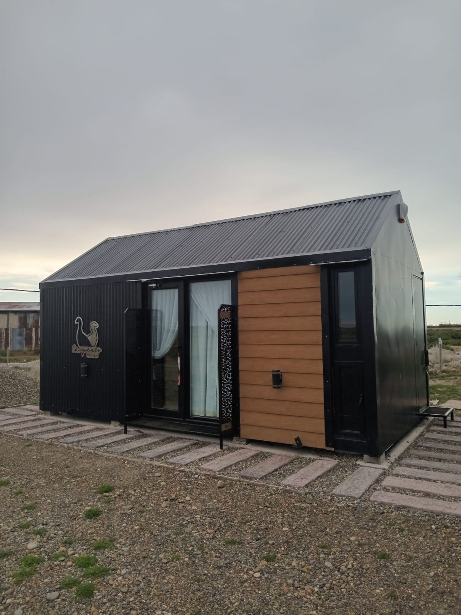 Fachada moderna de casa pré-fabricada com madeira e metal — projeto Rio Gallegos Tiny Houses, por TROKEN, em Río Gallegos