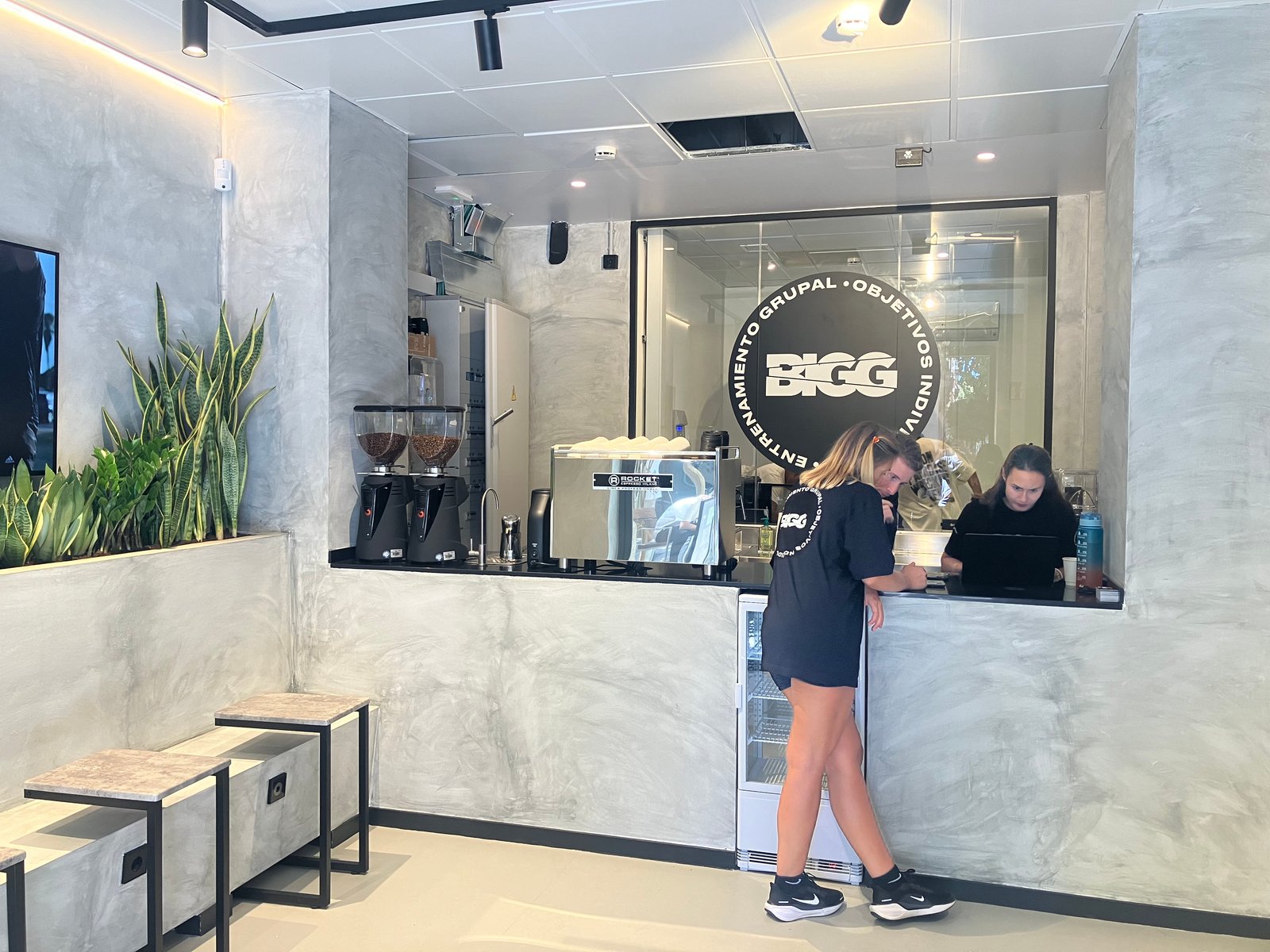 Cafetería con paredes de hormigón expuesto y mobiliario moderno — proyecto BIGG EIXAMPLE, por GeN Arquitectura, en Carrer del Consell de Cent