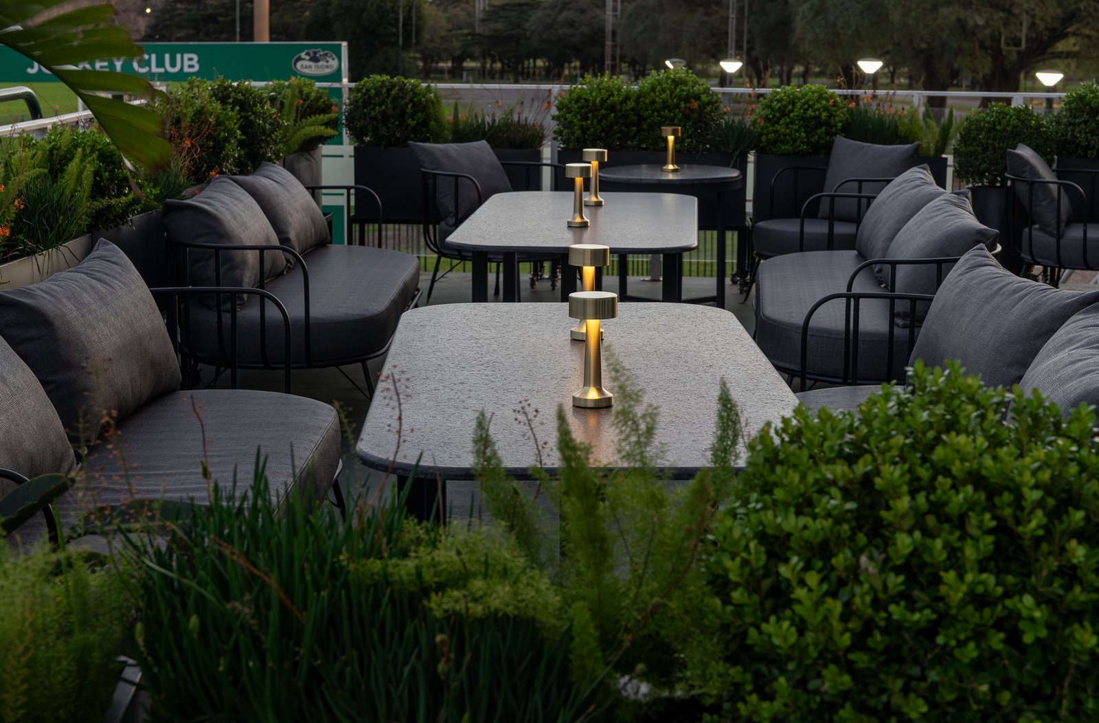 Área externa de hospitalidade com sofás de rattan e plantas — projeto PRESIDENTE BAR HIPODROMO, por AB ARQUITECTURA, em San Isidro