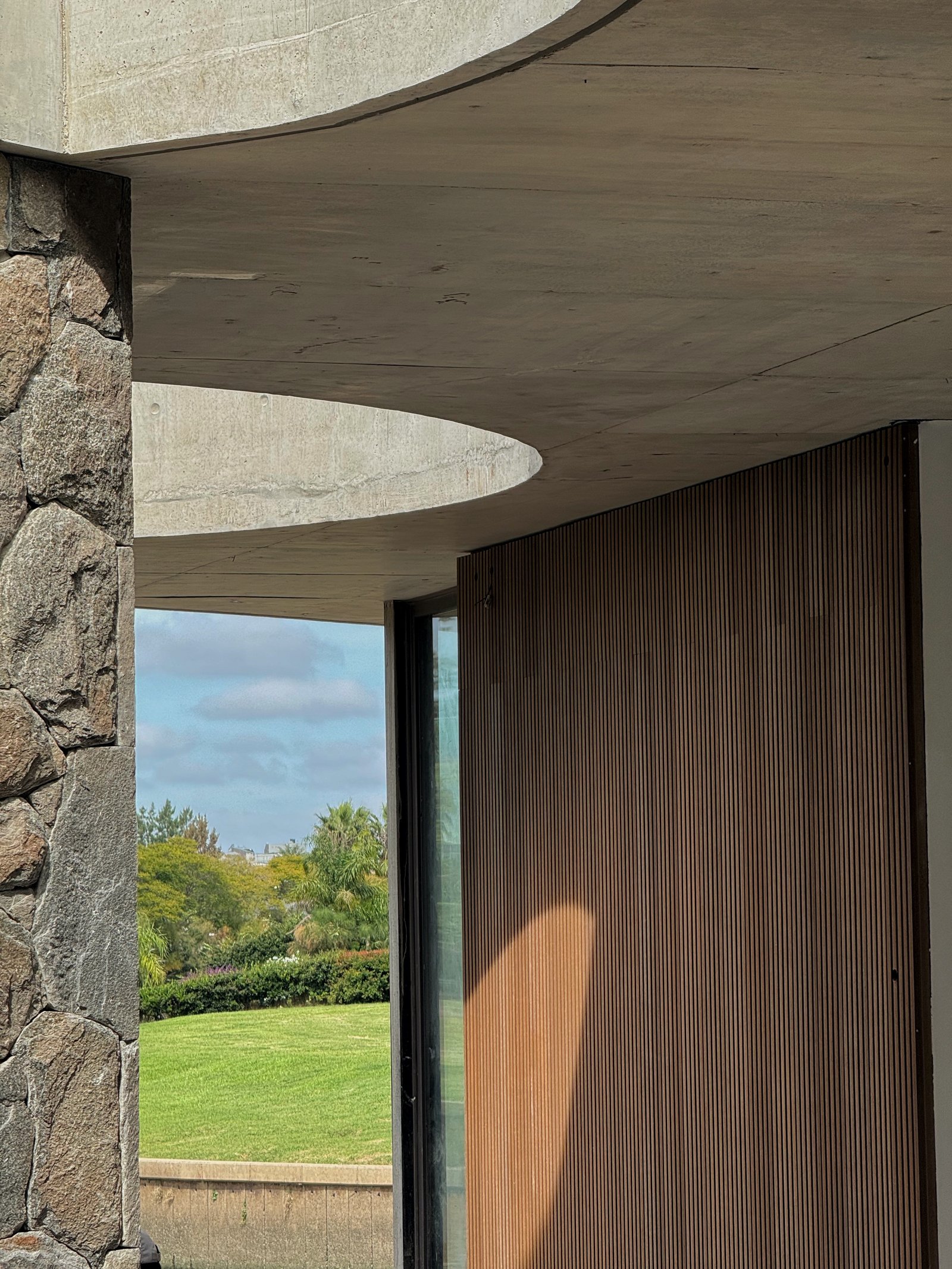 Entrada moderna con techo curvo de hormigón y puerta de madera — proyecto Obra Remy Architects, por lifecycle