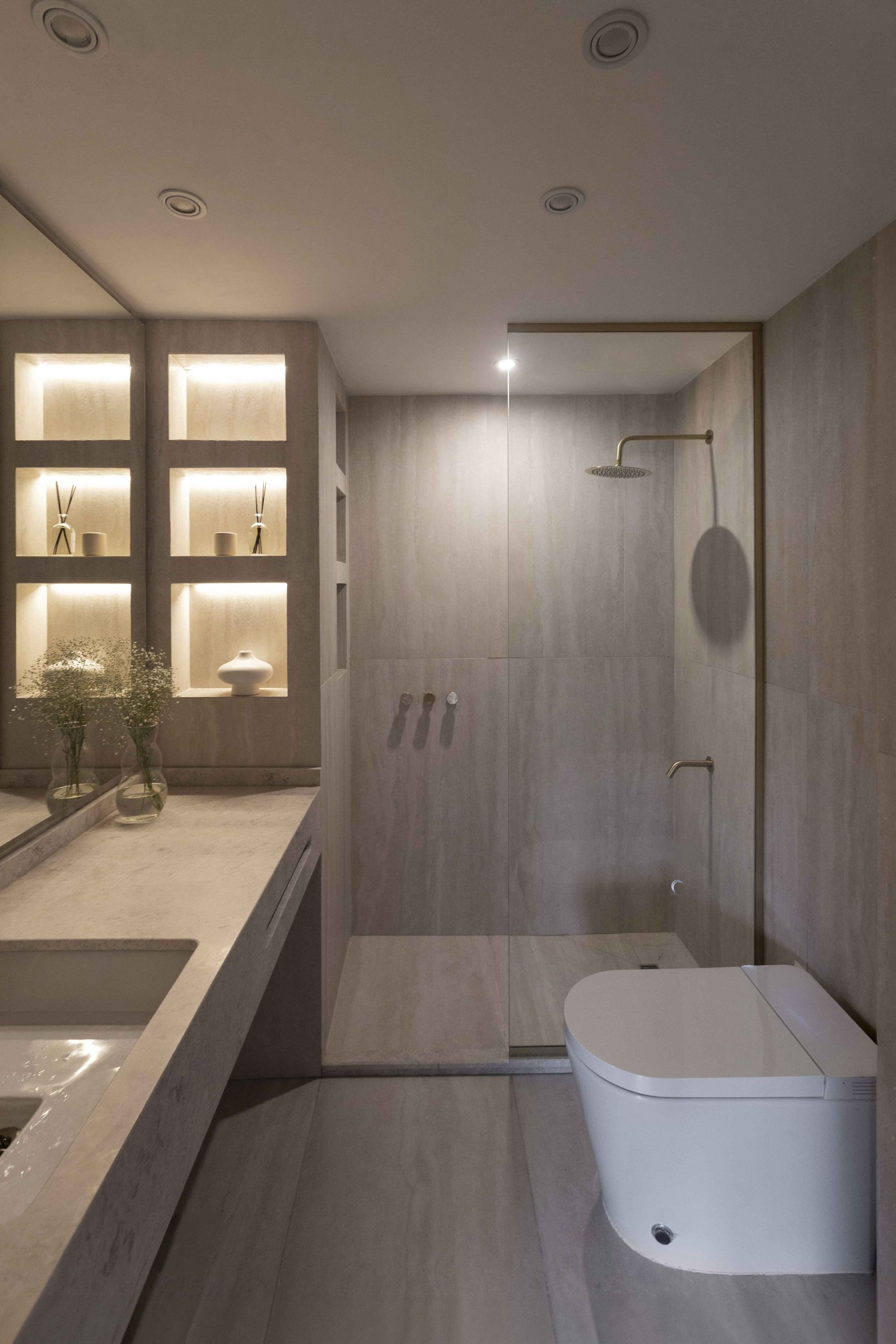 Banheiro moderno com prateleiras iluminadas e superfícies de pedra — projeto Libertador, por Bouré Studio, em Palermo