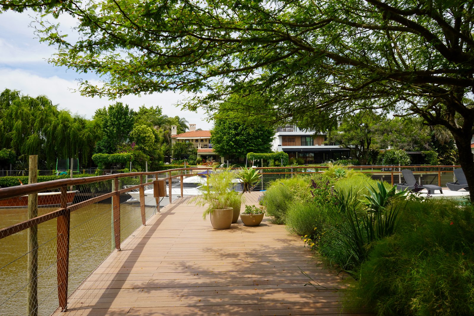 Sendero de madera con vegetación exuberante y vista al agua — proyecto Obra Boating, por lifecycle, en Náutico San Isidro - Punta Chica