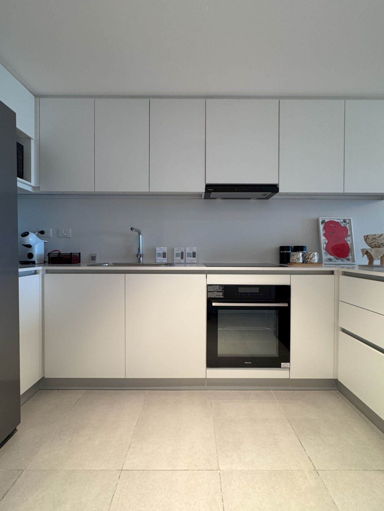 Cocina moderna blanca con electrodomésticos integrados y piso de piedra — proyecto PROYECTO BLISS - EDIFICIO MARINA, por ILVA, en Provincia de Buenos Aires