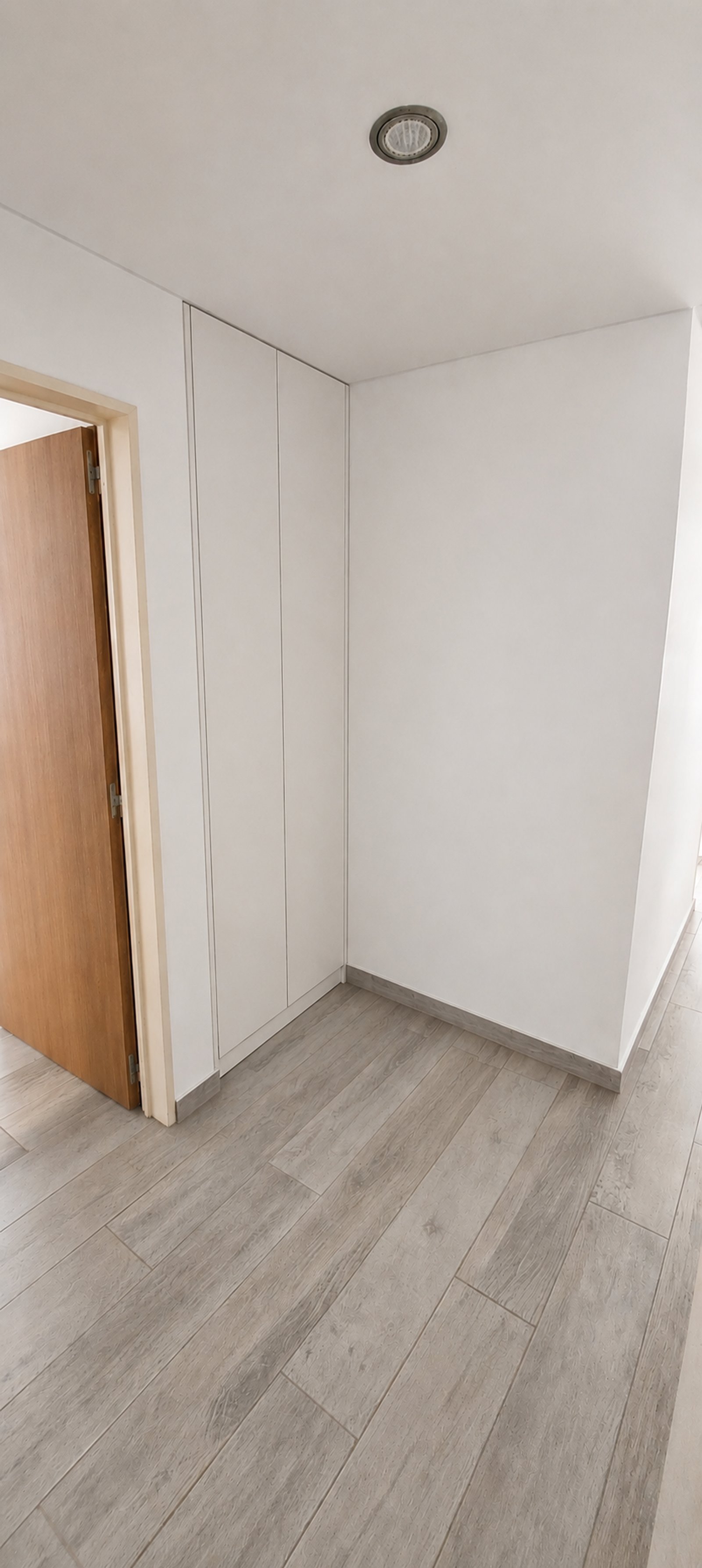 Corredor moderno com porta de madeira e armários brancos — projeto Interiorismo MyM, por Plasma co, em Lomas de Zamora