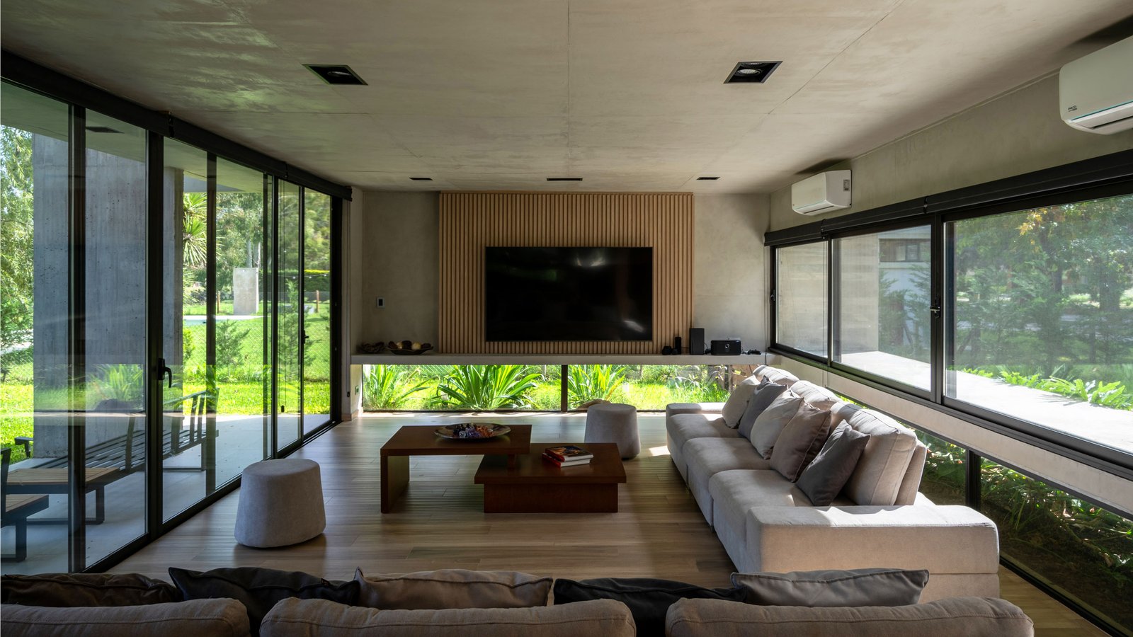 Living moderno con ventanales amplios y vista al bosque — proyecto Casa Miralagos II, por Besonías Almeida arquitectos, en La Plata