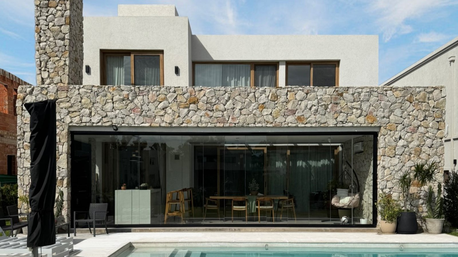 fachada moderna con piedra, vidrio y piscina integrada — proyecto Casa ER , por Hermann Arquitectos, en Arribeños 1611