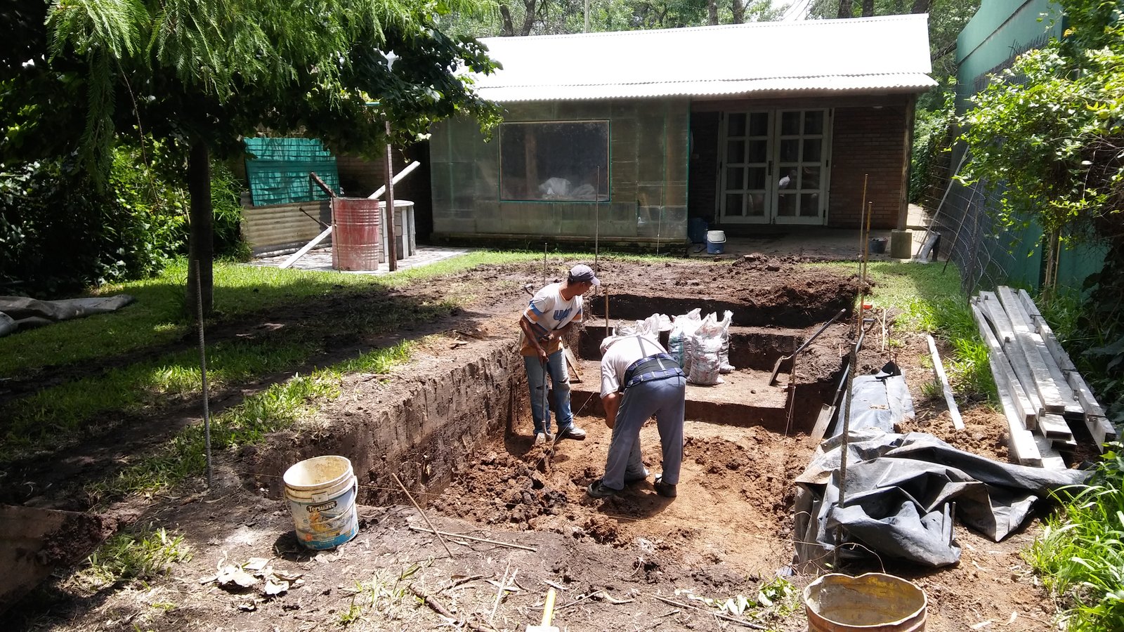 obra en patio trasero con materiales y excavación — proyecto Piscina de hormigón armado · Banco sumergido integrado, por OBRAMMOS, en Av. América 5553