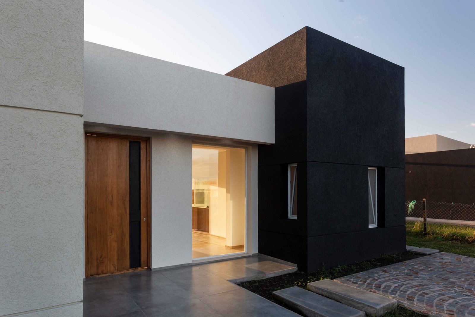 fachada moderna con contraste de volúmenes y madera — proyecto San Simon I, por Estudio Stepa, en Ezeiza