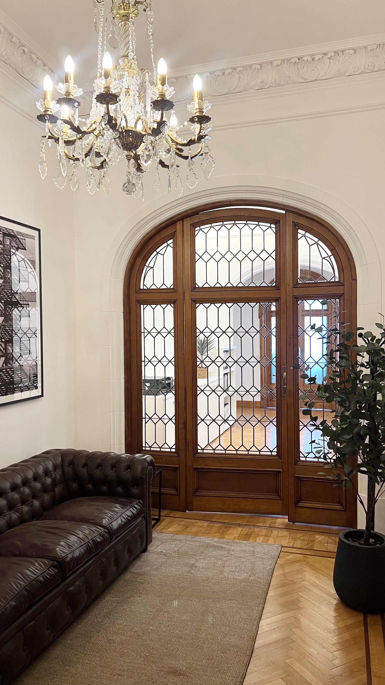 Living elegante con sofá Chester, araña de cristal y puertas arqueadas — proyecto MONTEVIDEO, por Estudio RG, en Recoleta