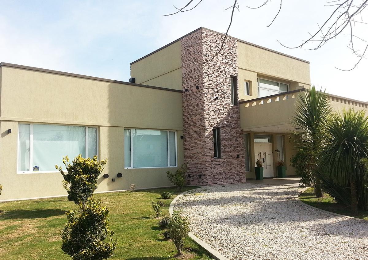 Fachada moderna de residência com estuque e pedra — projeto Casa Lopez, por Arquitectura UNO, em Buenos Aires
