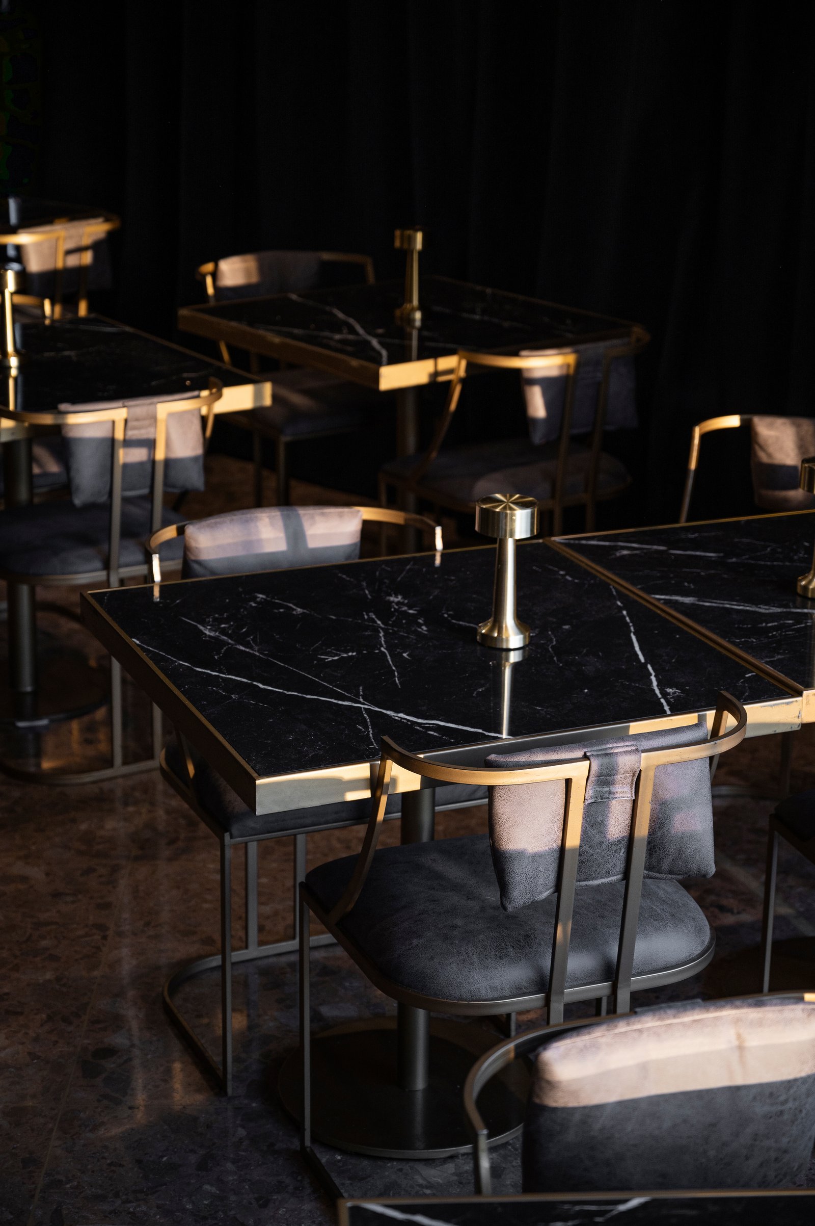 Mesas y sillas modernas de mármol negro en un comedor elegante — proyecto PRESIDENTE BAR HIPODROMO, por AB ARQUITECTURA, en San Isidro