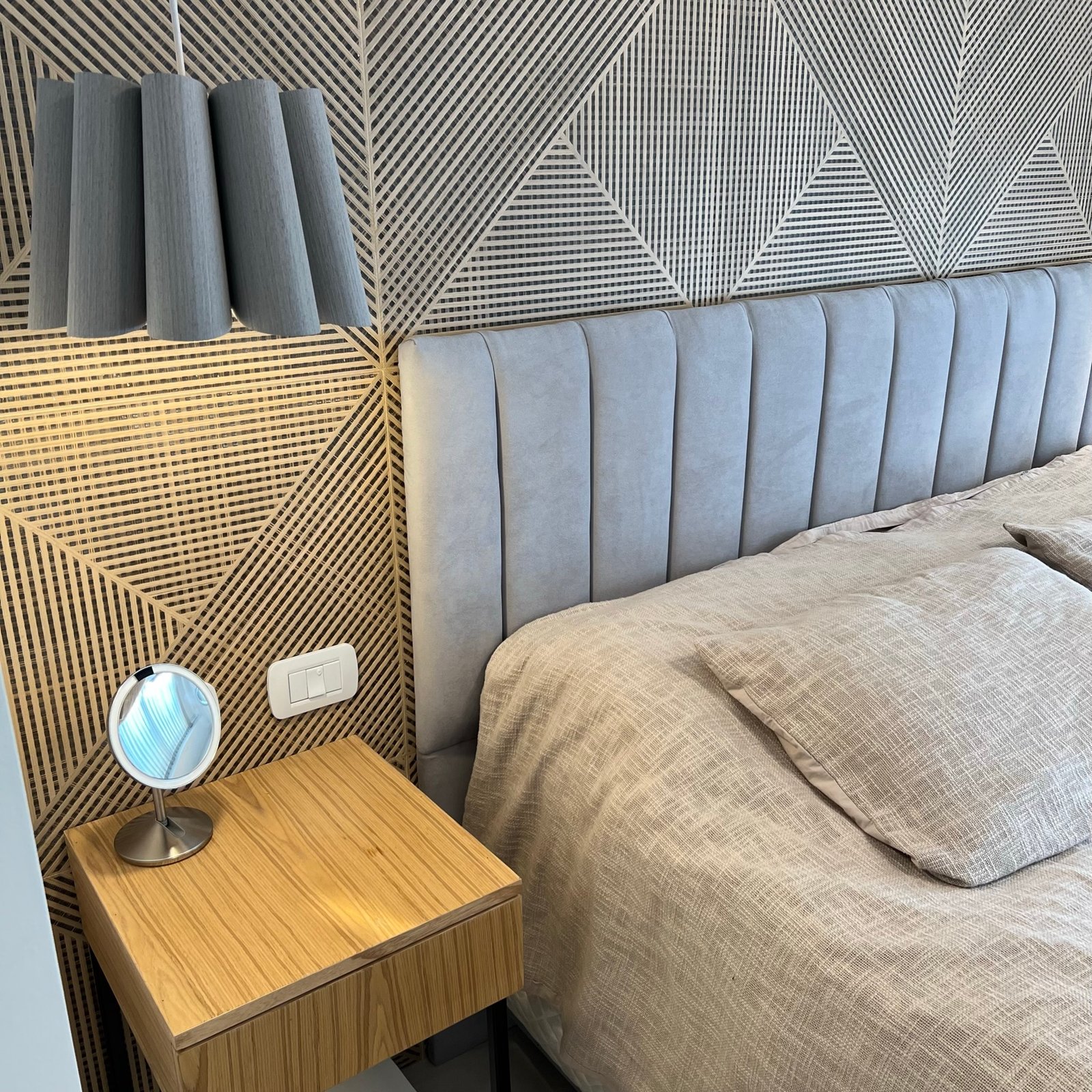Habitación moderna con pared de madera geométrica y cama beige — proyecto Basualdo II, por MDBK Arquitectura, en Liniers